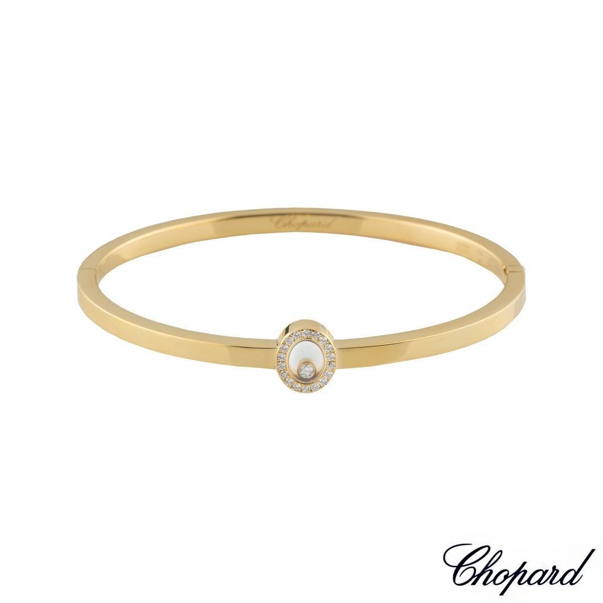 A dainty 18k yellow gold Chopard bangle from the Happy Diamonds collection. The bangle comprises of a diamond oval surround is set with 18 round brilliant cut diamonds, containing the signature floating diamond totalling 0.05ct, G colour and VS