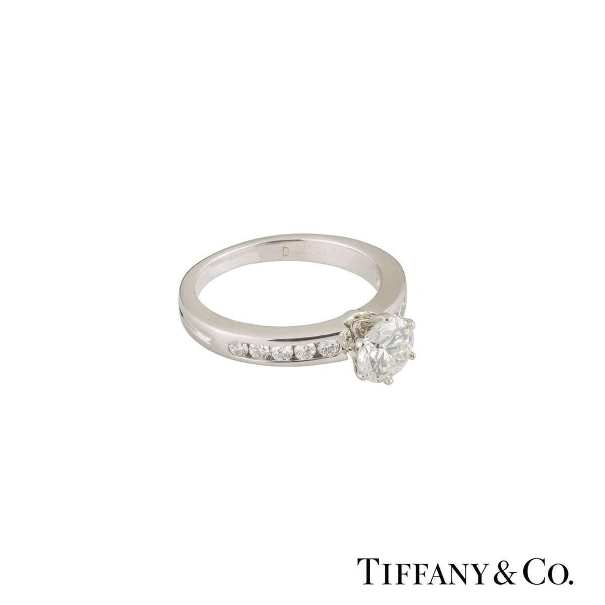 A beautiful Tiffany & Co. diamond engagement ring from The Tiffany Setting with Diamond Band collection. The ring comprises of a 0.76ct round brilliant cut diamond in a prong setting, G colour and VS1 clarity. The ring features 5 round brilliant cut