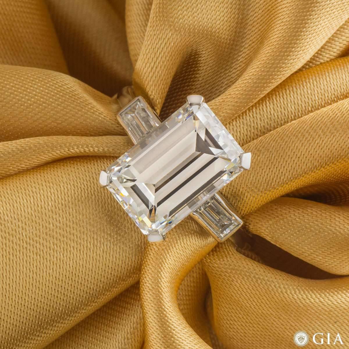 An exquisite diamond ring in platinum. The central claw set emerald cut diamond weighs 7.02ct, is H colour and VS1 in clarity. Flanked on either side are 2 baguette cut diamonds in a rubover setting, totalling approximately 0.80ct and well matched