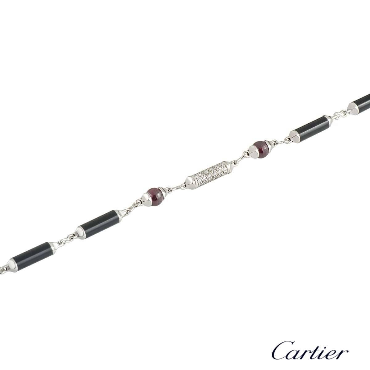 A unique 18k white gold diamond ruby and onyx Cartier bracelet from the Le Baiser Du Dragon collection. The bracelet comprises of  6 cylinder bar motifs, 4 with an onyx inlay and 2 with 79 round brilliant cut diamonds. The diamonds have a total