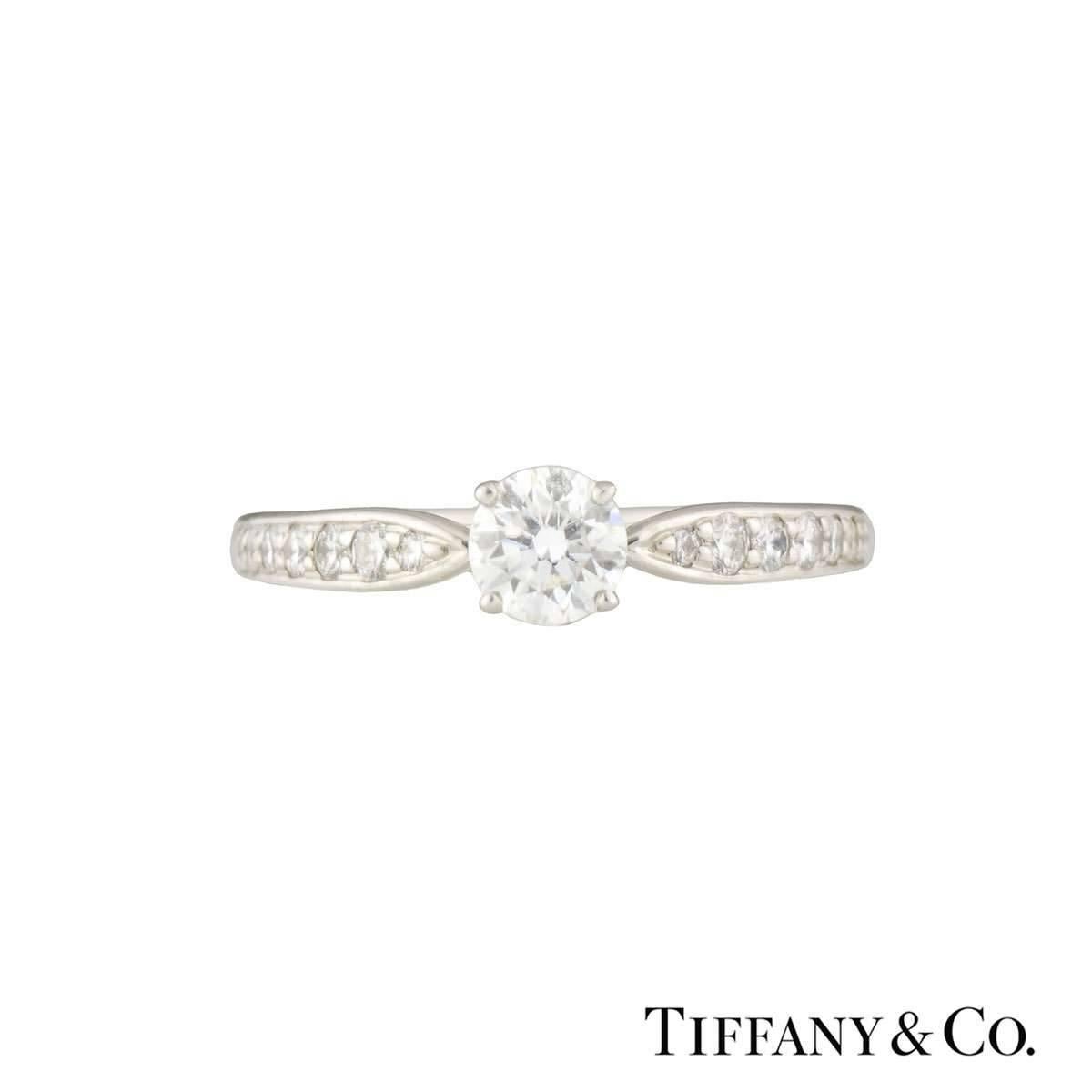 A stunning diamond Tiffany & Co. platinum ring from the Harmony collection. The ring is set to the centre with a round brilliant cut diamond weighing 0.32ct, F colour and VS2 in clarity. The ring has half diamond set shoulders totalling