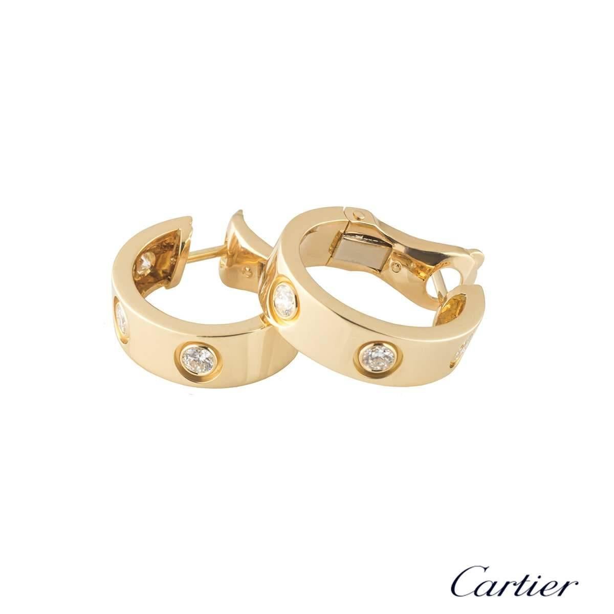 A pair of 18k yellow gold diamond earrings from the iconic Love collection by Cartier. Each hoop earring is set with 3 round brilliant cut diamonds. The earrings are 18mm in length and 5mm in width and feature a post and lever hinged fittings. The