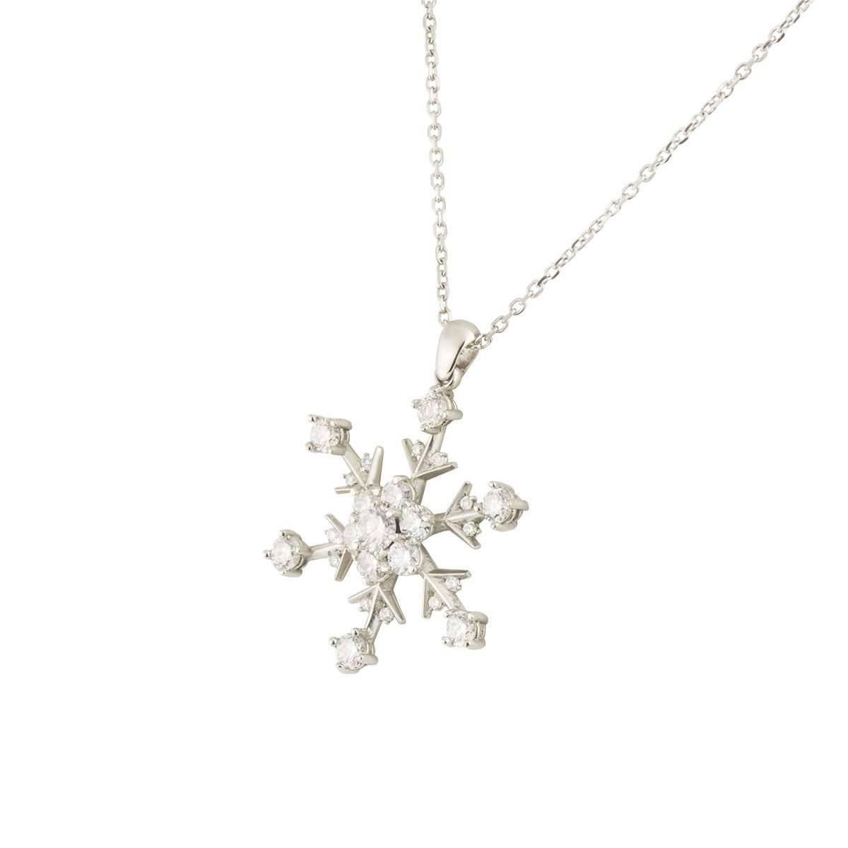 A beautiful platinum diamond pendant. The pendant comprises of a snowflake motif featuring a round brilliant cut diamond in the centre with a halo of diamonds, complemented with round brilliant cut diamonds set to the outer edges of the snowflake