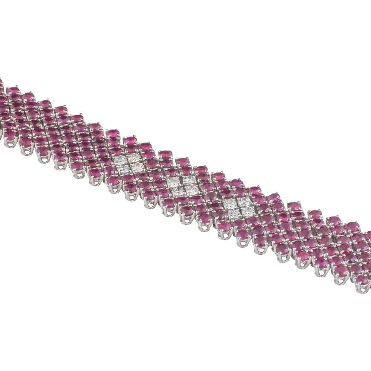 A vibrant 18k white gold diamond and ruby bracelet. The bracelet comprises of 241 round cut rubies in 4 claw setting dispersed between diagonal 7 rows. The rubies have a total weight of approximately 16.87ct, with a pinkish-red hue throughout.