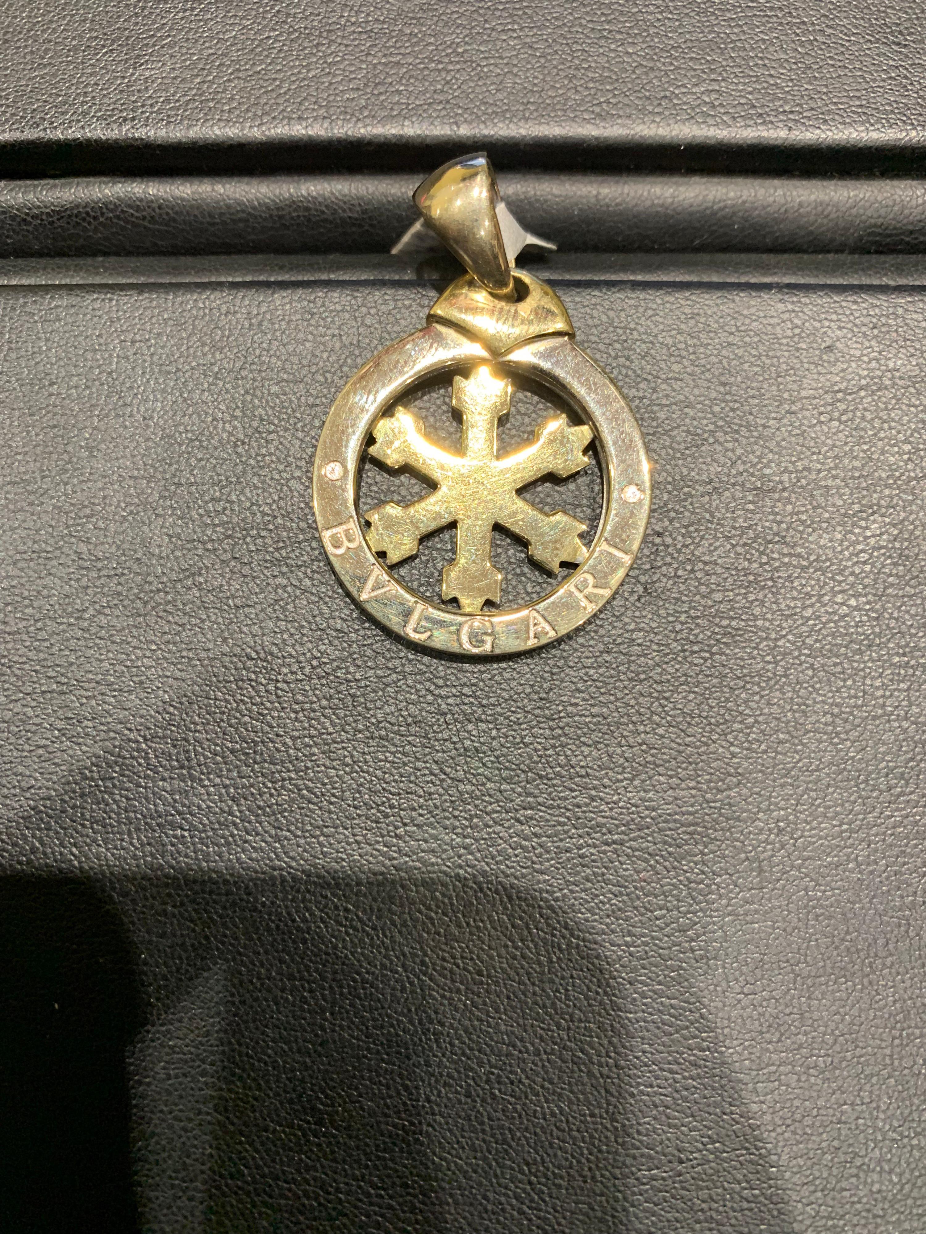 A snowflake stainless steel and 18k yellow gold Bvlgari Tondo pendant. The pendant is centred with an 18k yellow gold rotating snowflake design and features 'Bvlgari' engraved around the stainless steel outer edge. The pendant is 3.20cm in length