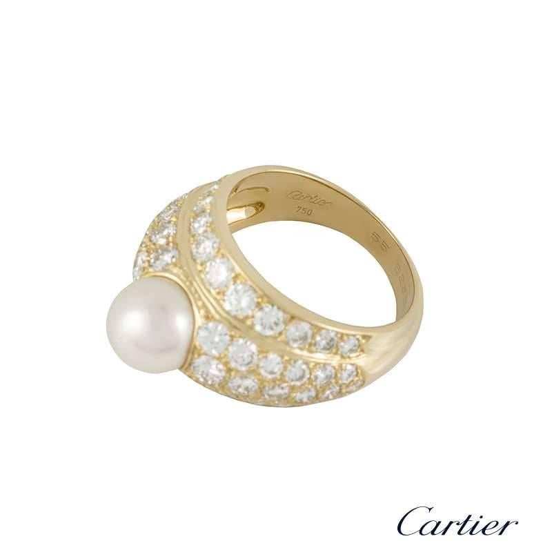 A stunning 18k yellow gold diamond and pearl dress ring from Cartier. The raised bomb style ring is set to the centre with an 8mm round cultured pearl, complemented by a pave set, graduating round brilliant cut diamonds surround. The diamonds total
