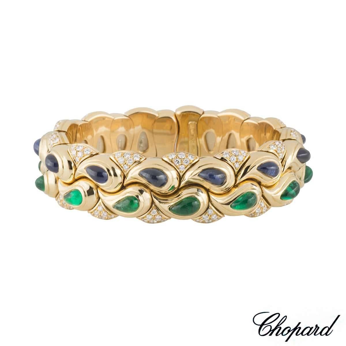A unique 18k yellow gold Chopard bangle from the Casmir collection. The bangle comprises of a a series of drop motifs set with cabochon sapphire and emerald gemstones. The sapphire cabochon totals approximately 6.50ct with a deep blue hue