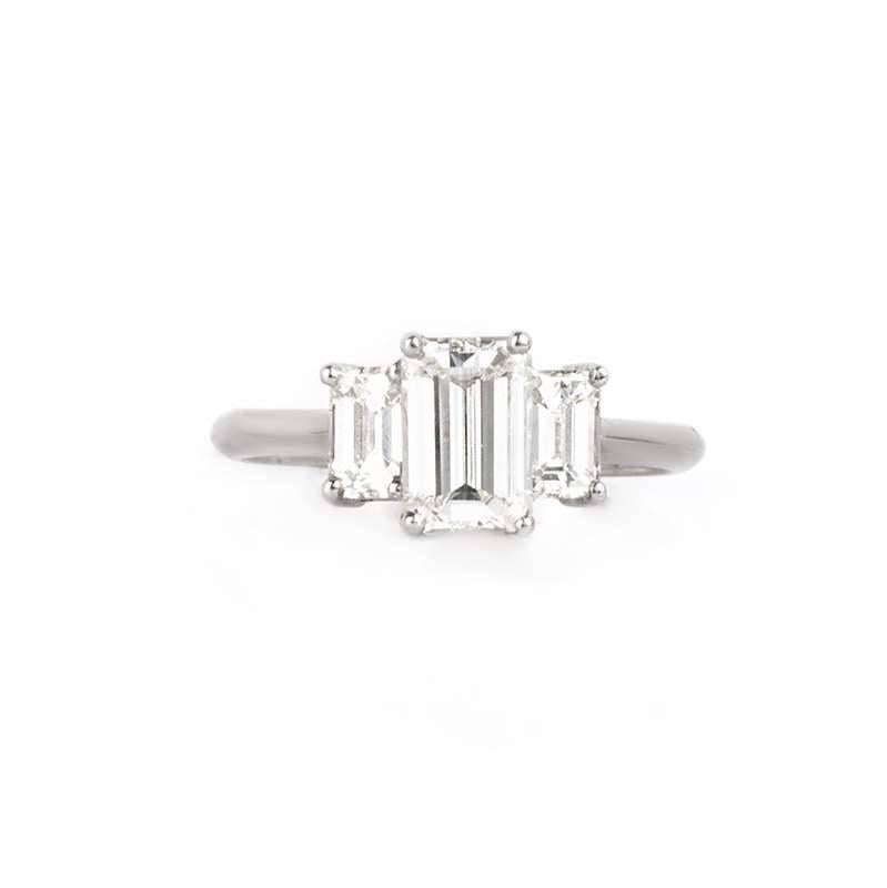 A striking 3 stone emerald cut diamond ring. The large centre stone is 1.15ct, I,J in colour and is VS2 in clarity, it is accompanied by 2 stones on either side which are well matched to the central stone. The current ring size of this ring is UK L,