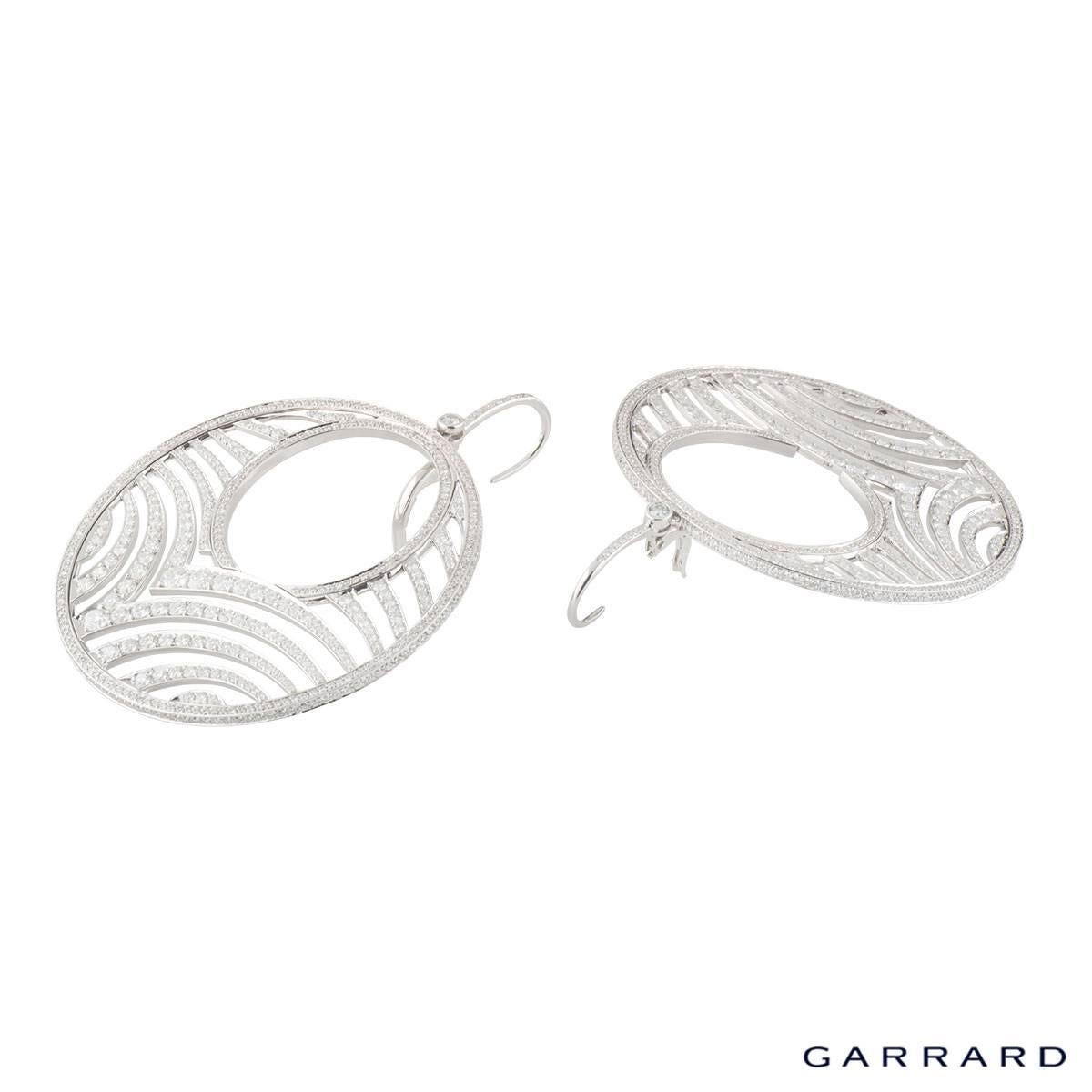 A sparkly 18k white gold Garrard diamond hoop earrings. The hoops comprise of a an open work circular motif encrusted with round brilliant cut diamonds with a weight of approximately 12.30ct, G colour and VS clarity. The earrings feature a