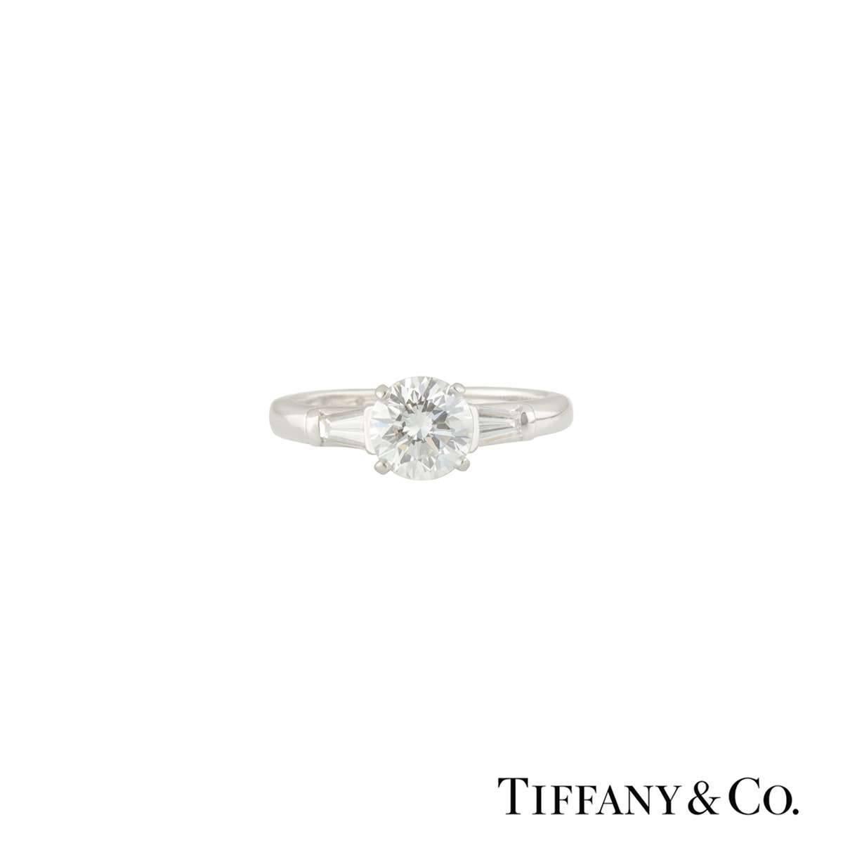 A stunning Tiffany & Co. diamond platinum engagement ring from the Three Stone collection. The ring comprises of a single round brilliant cut diamond in a 4 claw setting with a total weight of 1.17ct, H colour and VVS2 clarity. Flanked by two