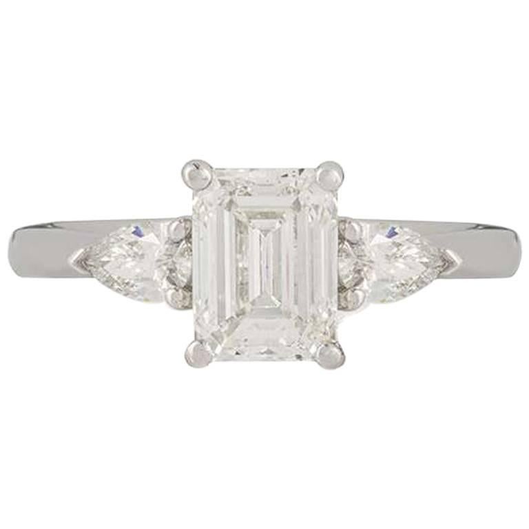 An 18k white gold diamond ring. The ring is set to the centre with a 1.17ct emerald cut diamond, G colour and VVS2 in clarity set within a classic four claw mount. Complementing the central stone are single pear cut diamonds set each side totalling