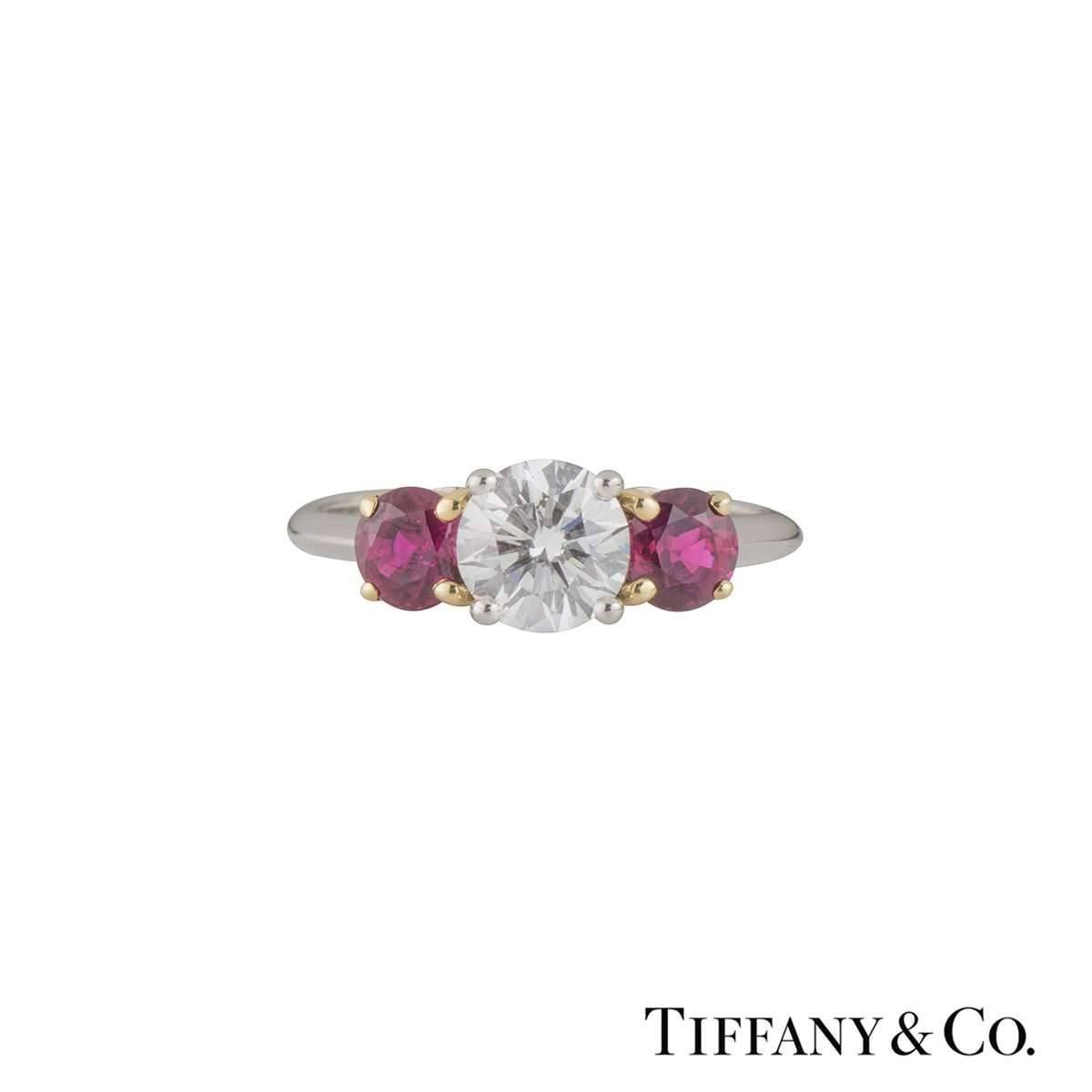 A luxurious platinum and 18k yellow gold Tiffany & Co. diamond and ruby ring from the Three Stone with Ruby collection. The ring comprises of a round brilliant cut diamond in a 4 claw setting in a platinum band. Complementing the centre diamond are
