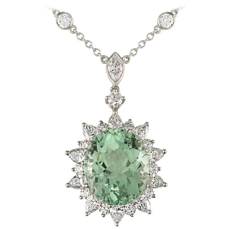 A stunning oval tourmaline and diamond pendant in platinum by Tiffany & Co. The pendant is set to the centre with a 8.59ct oval faceted green tourmaline which disperses a vivid green hue throughout. Complementing the central stone is a halo of round