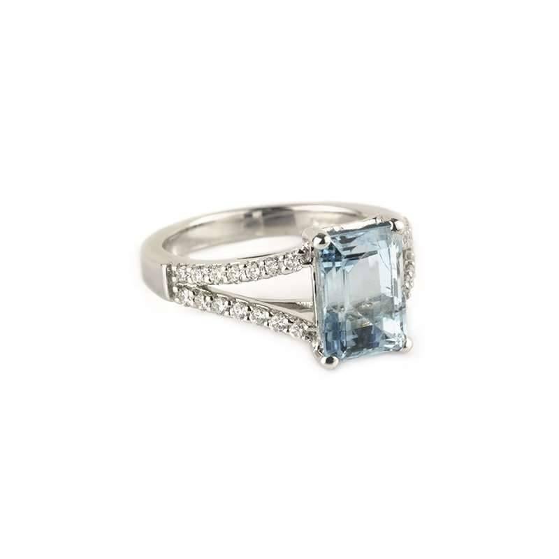 An stunning aquamarine and diamond ring. The impressive step cut aquamarine weighs approximately 2.30ct and is set between diamond set shoulders. The split shank is set with 28 round brilliant cut diamonds totalling approximately 0.25ct, H colour