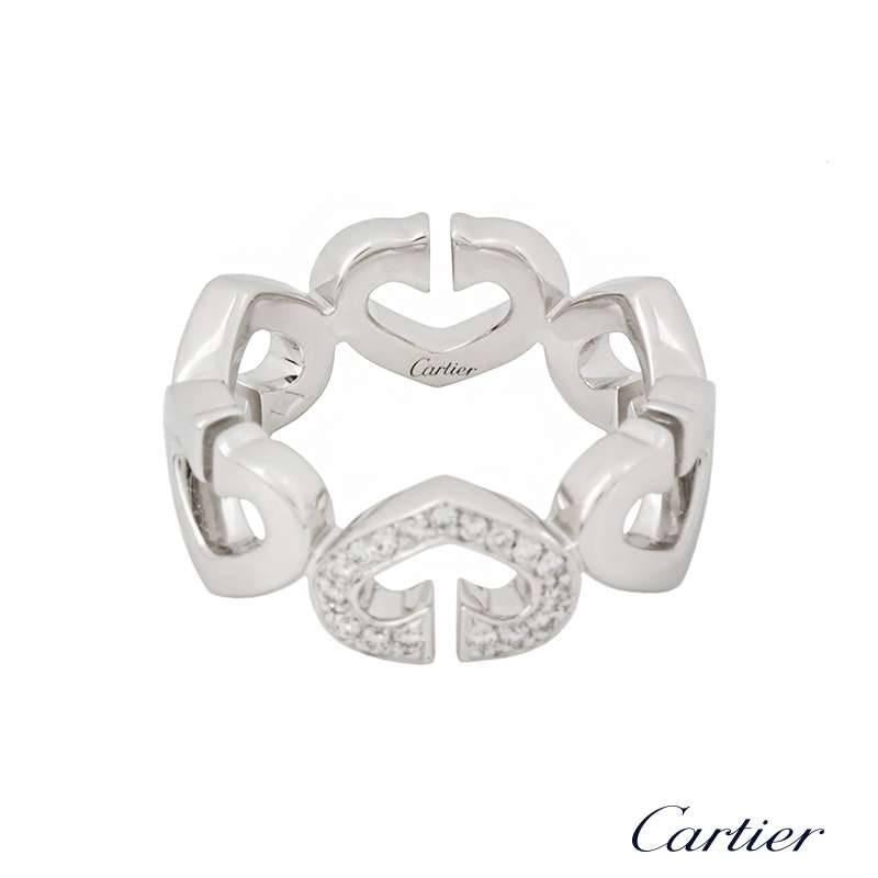 An iconic 18k white gold Cartier ring from the Hearts and Symbols collection. The 6 signature 'double C's' are joined to form small open work heart motifs, set to the centre with a single pave set heart motif. The ring is a US size 4 1/2, EU size 48