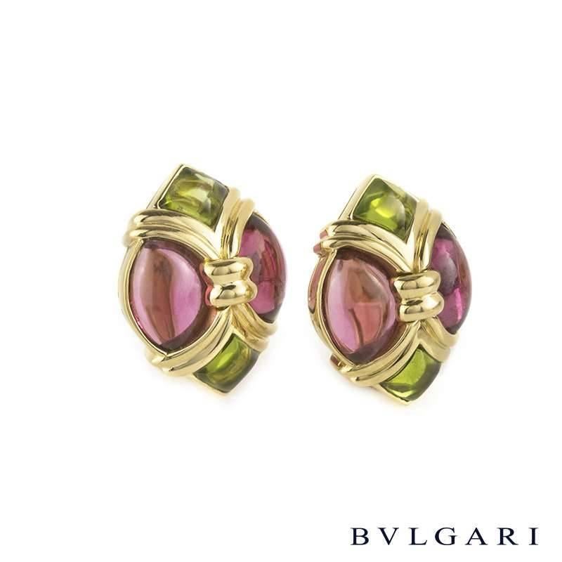 A pair of 18k yellow gold gem set earrings by Bvlgari. Each earring features an 18k yellow gold bowed navette design set with 2 oval cabochon pink tourmaline's and 2 green tourmaline's either side. The earrings are signed Bvlgari and measure
