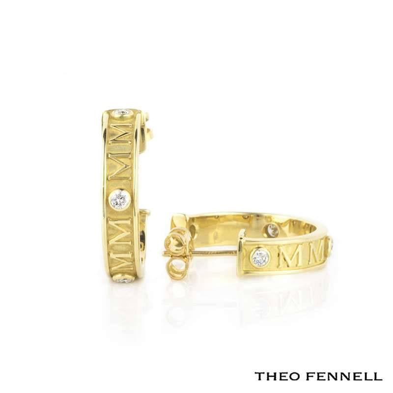 A pair of 18k yellow gold diamond set hoop earrings from the Theo Fennell Fennellium collection. Each hoop is set with four round brilliant cut diamonds totalling 0.16ct, featuring the engraving 'MM' in between each stone. The half hoops measure