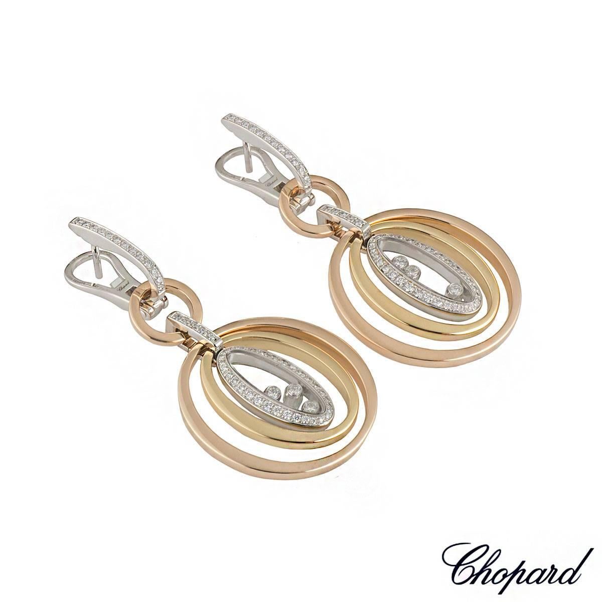 A stylish 18k tri-colour Chopard drop earrings from the Happy Diamonds collection. The earrings comprises of a hoop with round brilliant cut diamonds in a claw setting complemented with 3 circular motifs freely moving inside one another. The centre