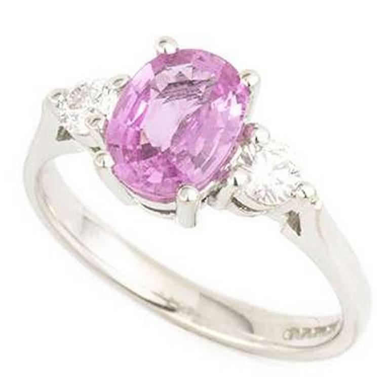 A gorgeous 3 stone pink sapphire and diamond ring in 18k white gold. The ring is centred with an oval cut pink sapphire weighing approximately 1.25ct. The stone is set between 2 round brilliant cut diamonds with a total diamond weight of 0.26ct, the