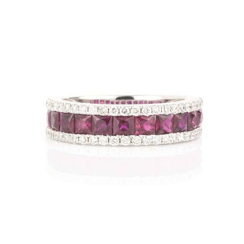 An outstanding ruby and diamond half eternity ring in 18k white gold. The ring is set to the centre with 11 square cut rubies of a rich and even hue throughout totalling 1.65ct. Complementing the rubies are a framed border of 46 round brilliant cut