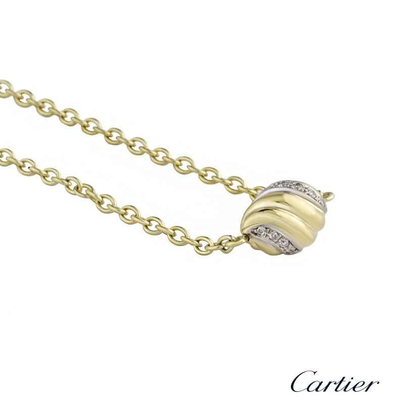 An 18k yellow gold diamond set swirl pendant by Cartier. The pendant is set in an oval swirl design motif and is accentuated with pave set round brilliant cut diamonds set in 18k white gold, running through the centre totalling approximately 0.10ct.