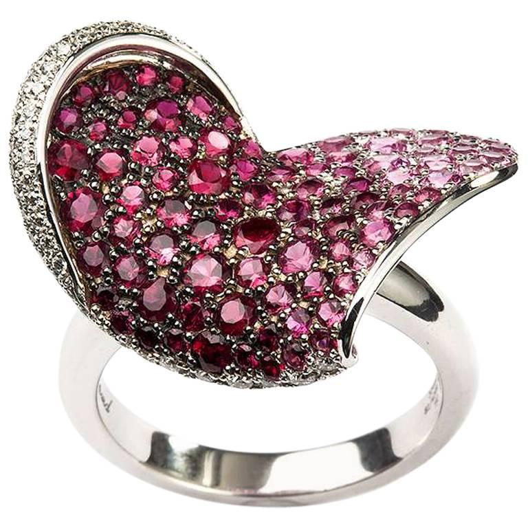 An 18k white gold heart shape ring from Chopard. The ring has 67 diamonds totalling 0.34ct set around one side of the heart. The centre of the ring is made up of 40 rubies weighing 0.55ct and 54 pink sapphires weighing 1.12ct. The ring is a US size