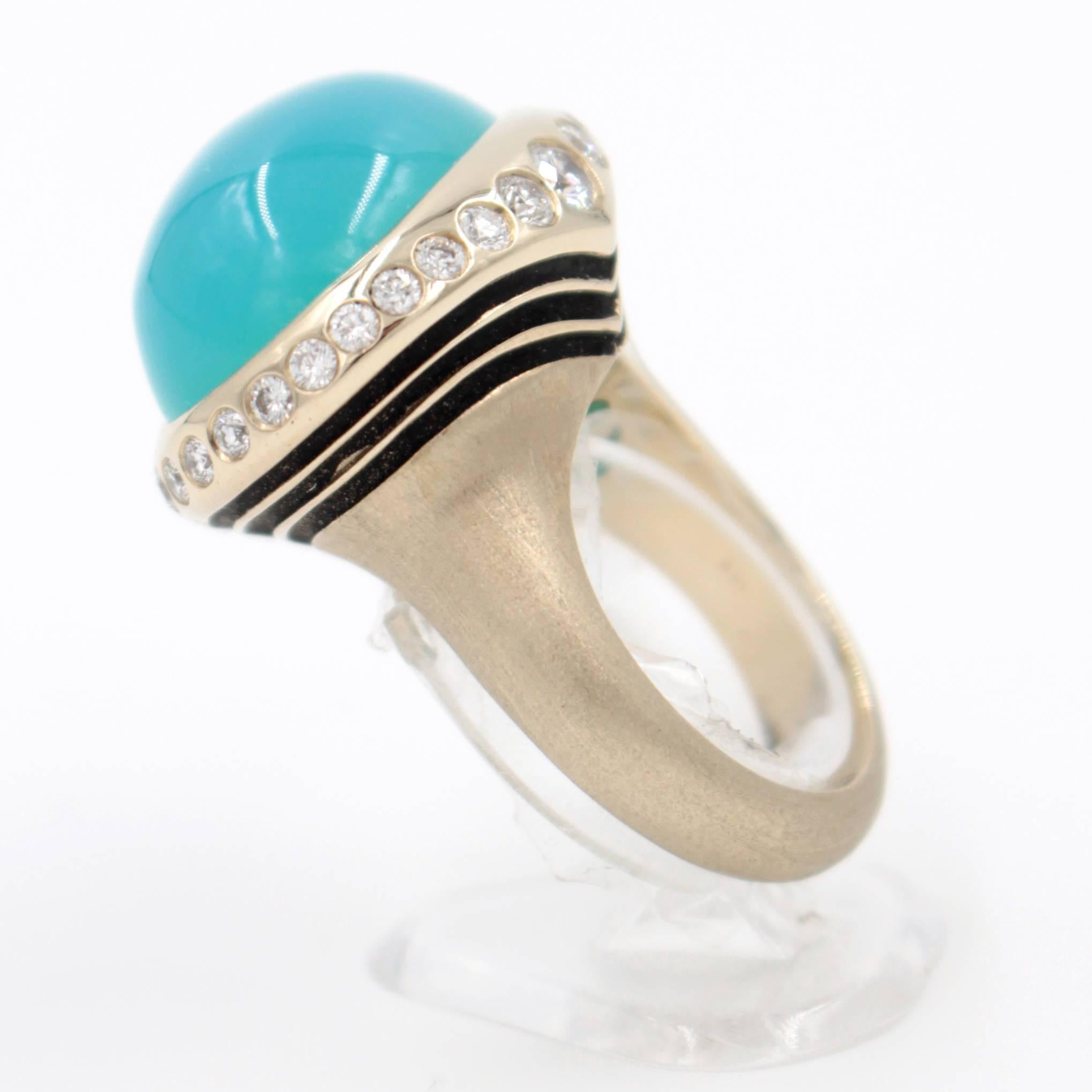 This delightful  ring is 18 karat yellow gold set with a large blue 20 carat chalcedony cabochon surrounded by .96 carats of round brilliant diamonds.