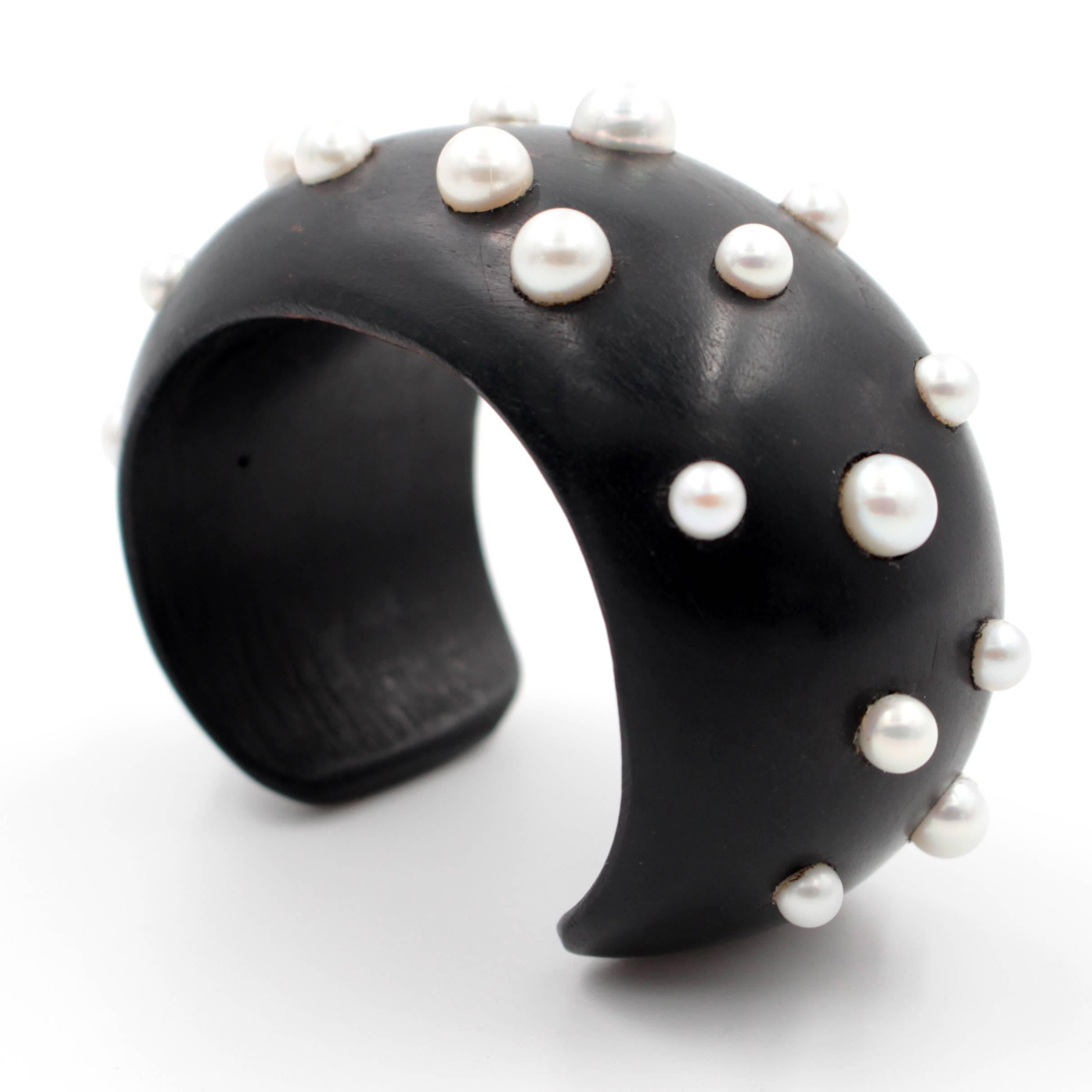 This chic ebony wood cuff bracelet features pearls set with 18 karat yellow gold screws. This unique piece may be worn with formal attire or with jeans for a casual look.