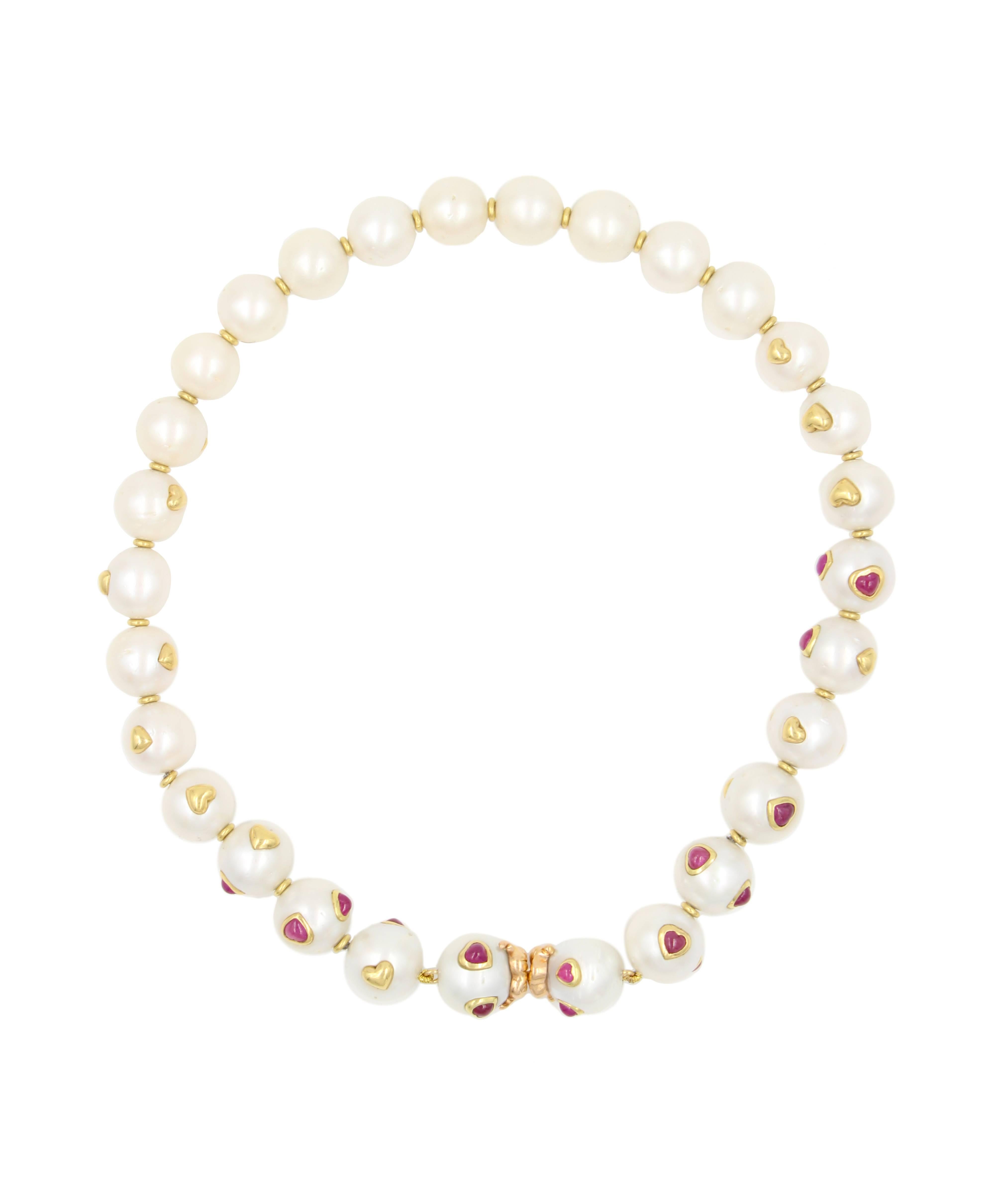 The Be My Valentine Necklace is a lustrous strand of pearls that feature heart shaped Ruby cabochons set in the South Sea Pearls in 18 karat gold bezels. The clasp is actually lips carved out of gold so when it is clasped the two sweethearts are