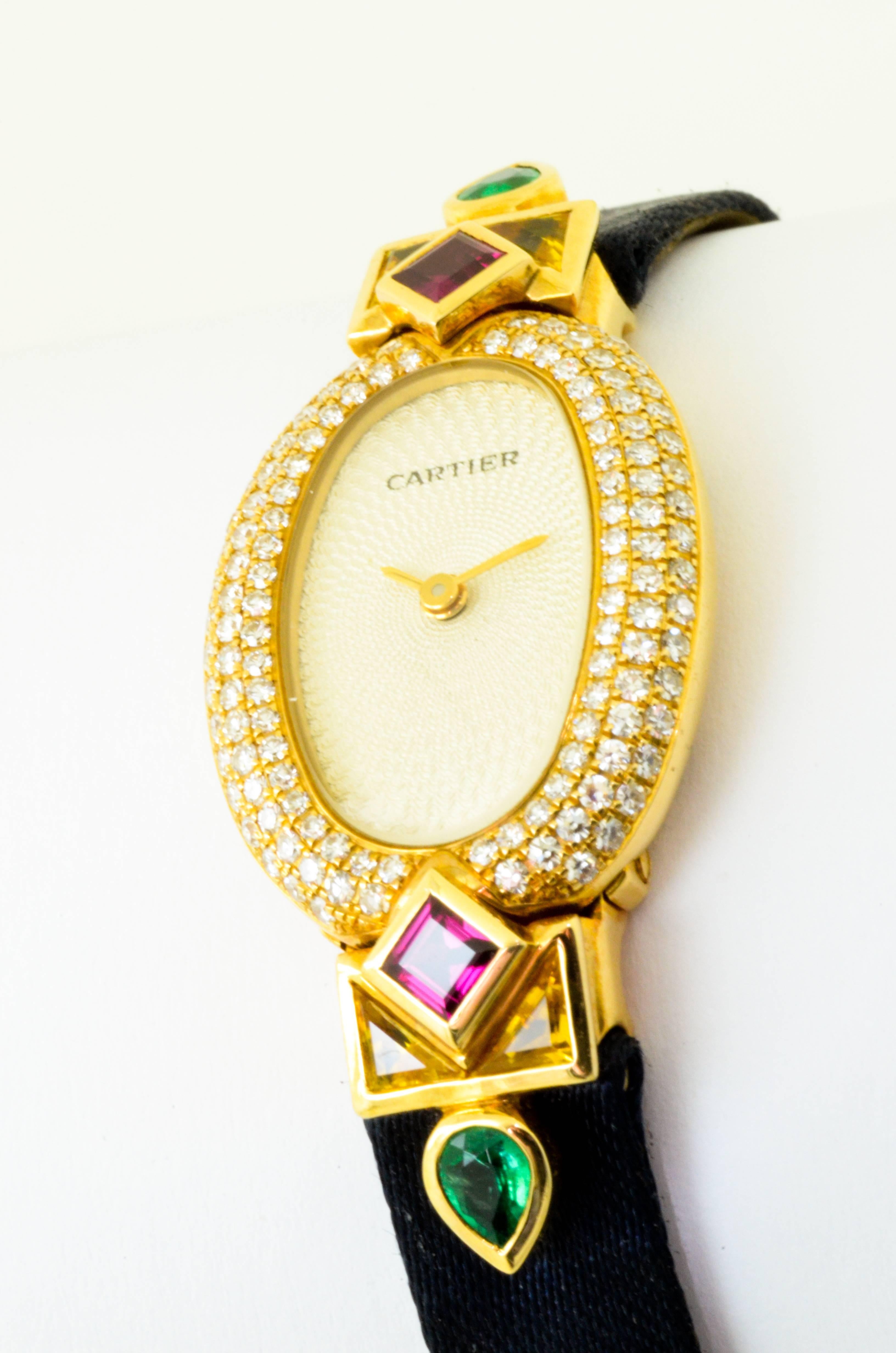 A stunning vintage Cartier 1960 ladies wrist watch set in 18 karat yellow gold with original set diamond, emerald, ruby and sapphire detailing.

Bracelet is both silk and leather with original 'Cartier Paris'.


