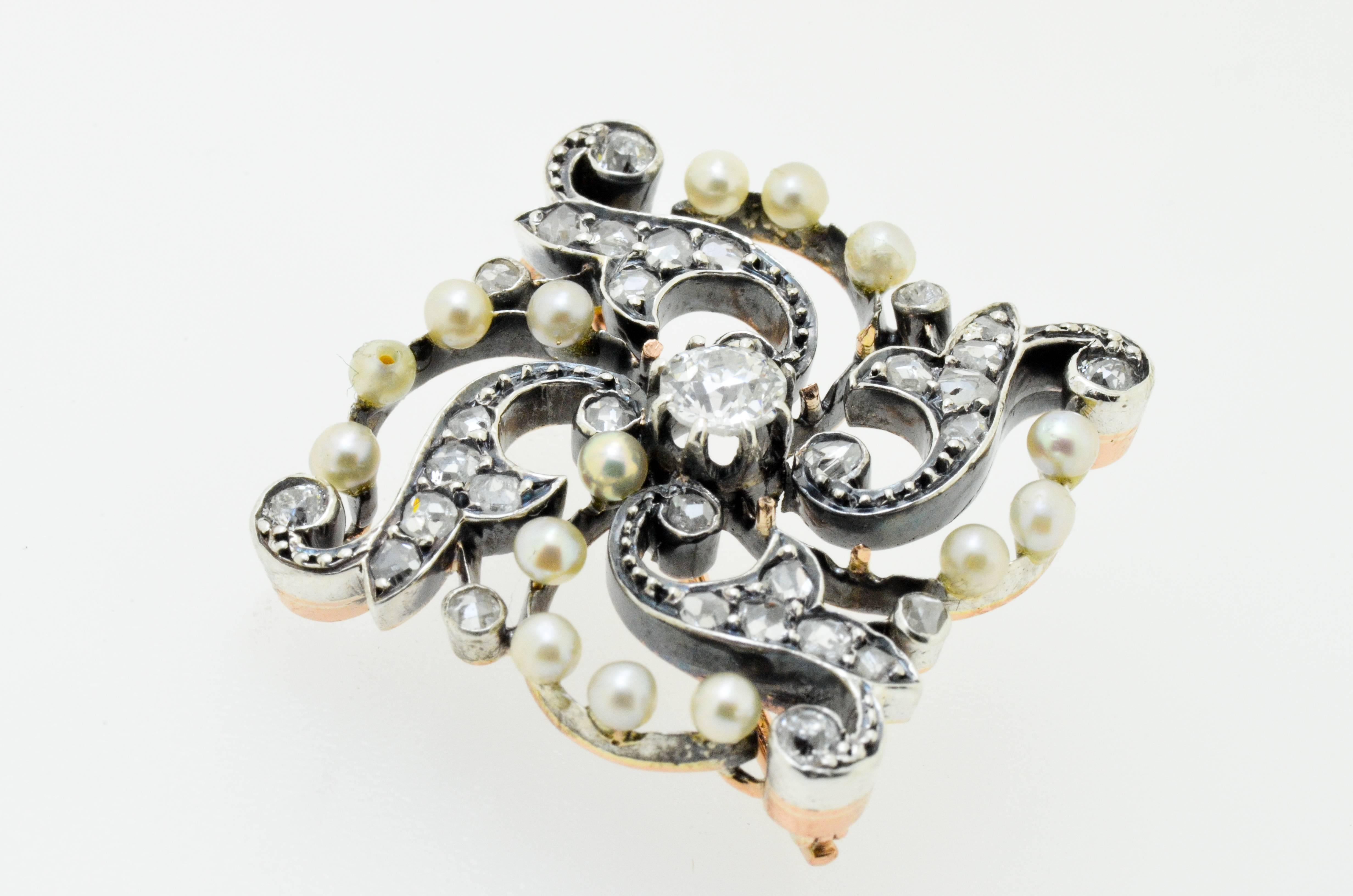 Gold and silver brooch set with a clean white 0.25 carat diamond centre stone and with numerous pearls and rose cut diamonds on surround.