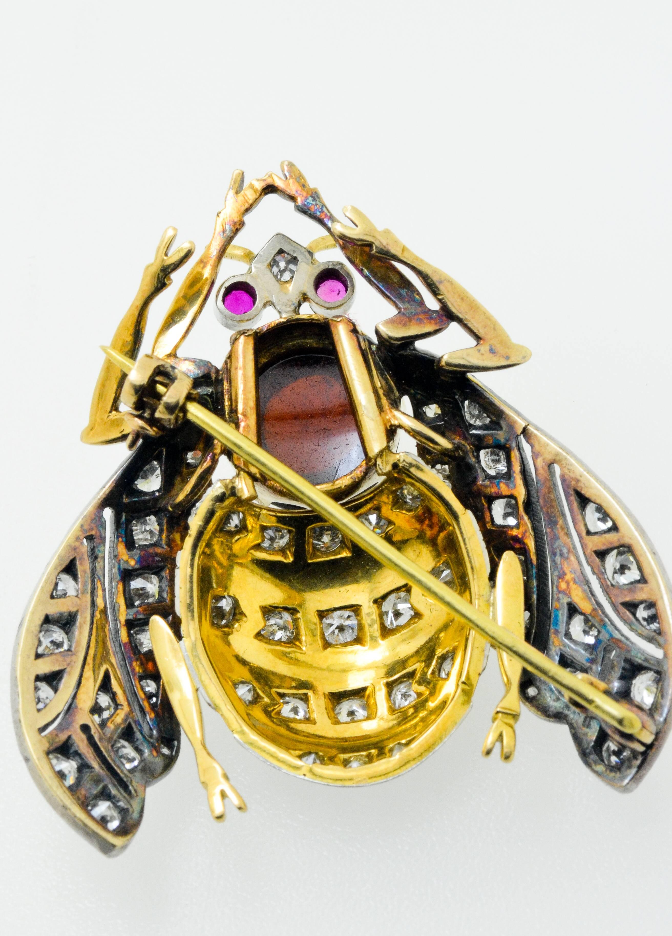 Beauitful insect brooch set in 18 karat white and yellow gold consisting of 3 carats of clean white brilliant cut diamonds, a black enamel and cabochon gemstone centre stone and ruby eyes.