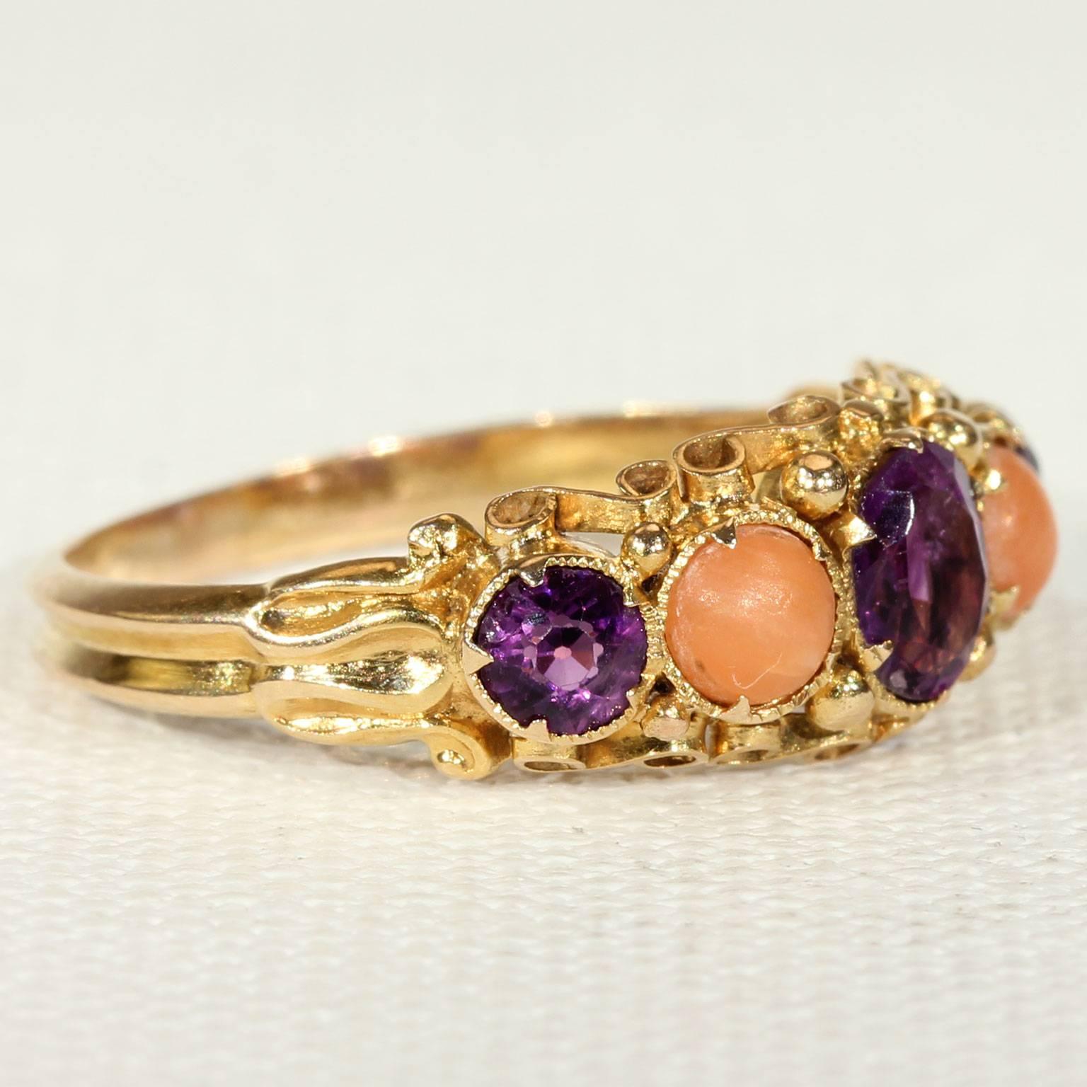 This wonderful Antique Victorian coral and amethyst ring was handcrafted in 12 karat gold. It was made in Europe around 1870. This ring holds two peach colored corals, both cabochon cut and oh, so lovely. They each measure 4.6 mm in diameter and 1.6