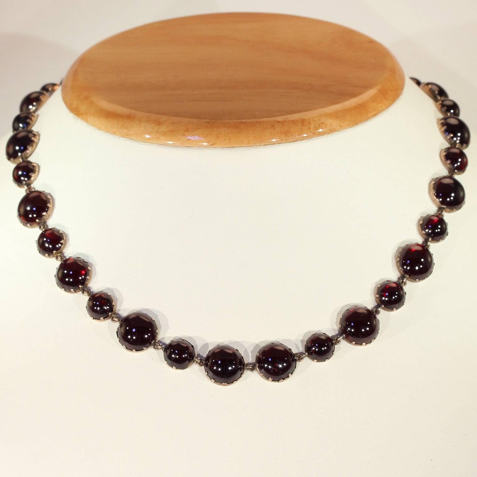 This golden chain of smooth cabochon garnets was handcrafted around 1820. It was made during the Georgian era, in England, and features 15 inches of deep red round cabochon cut stones, 120 carats in total. Large and small garnets are patterned
