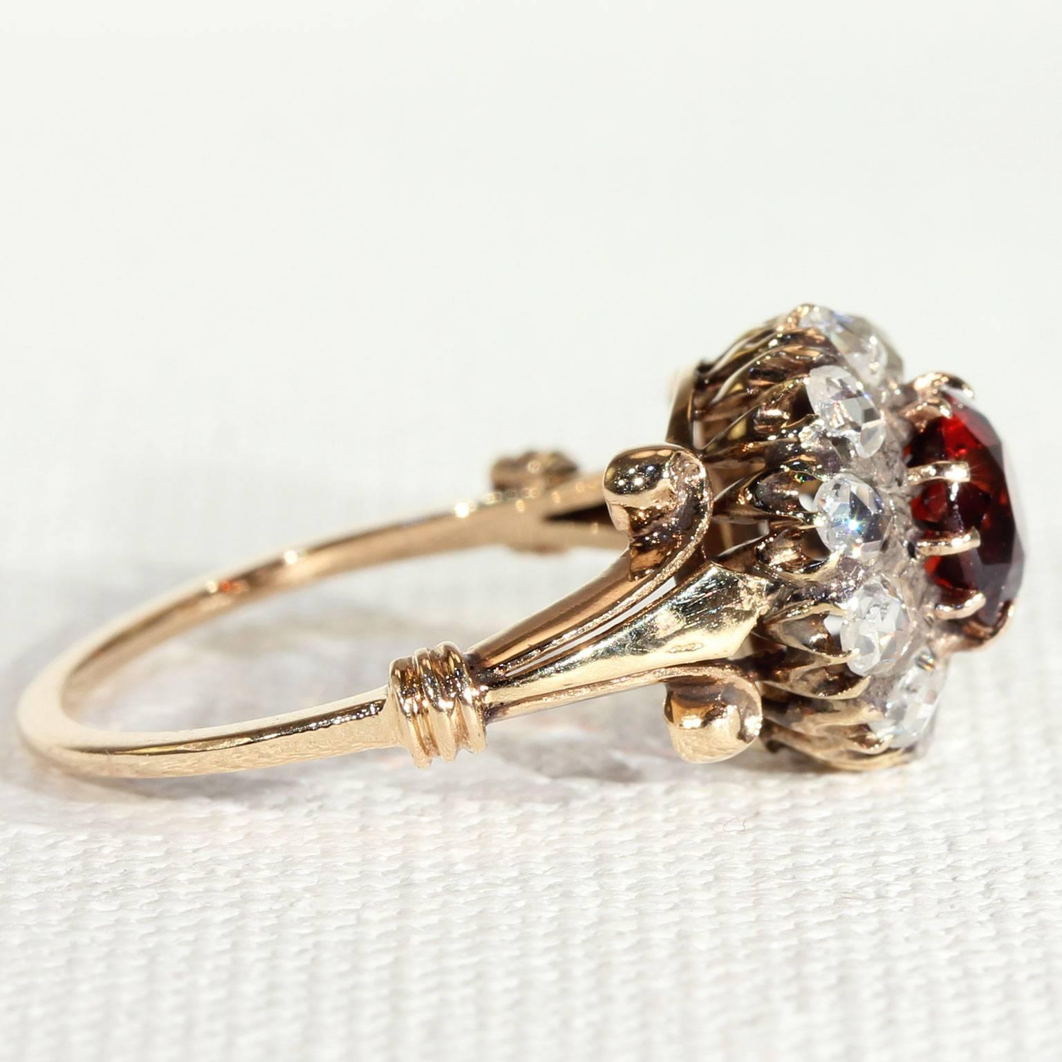 This wonderful antique Victorian cluster ring was hand made in England around 1890. It is crafted in 18 karat gold and is set with one round faceted Hessonite Garnet which weighs about 1.1 carats. The garnet is set in a halo of 10 2.3 mm rose cut