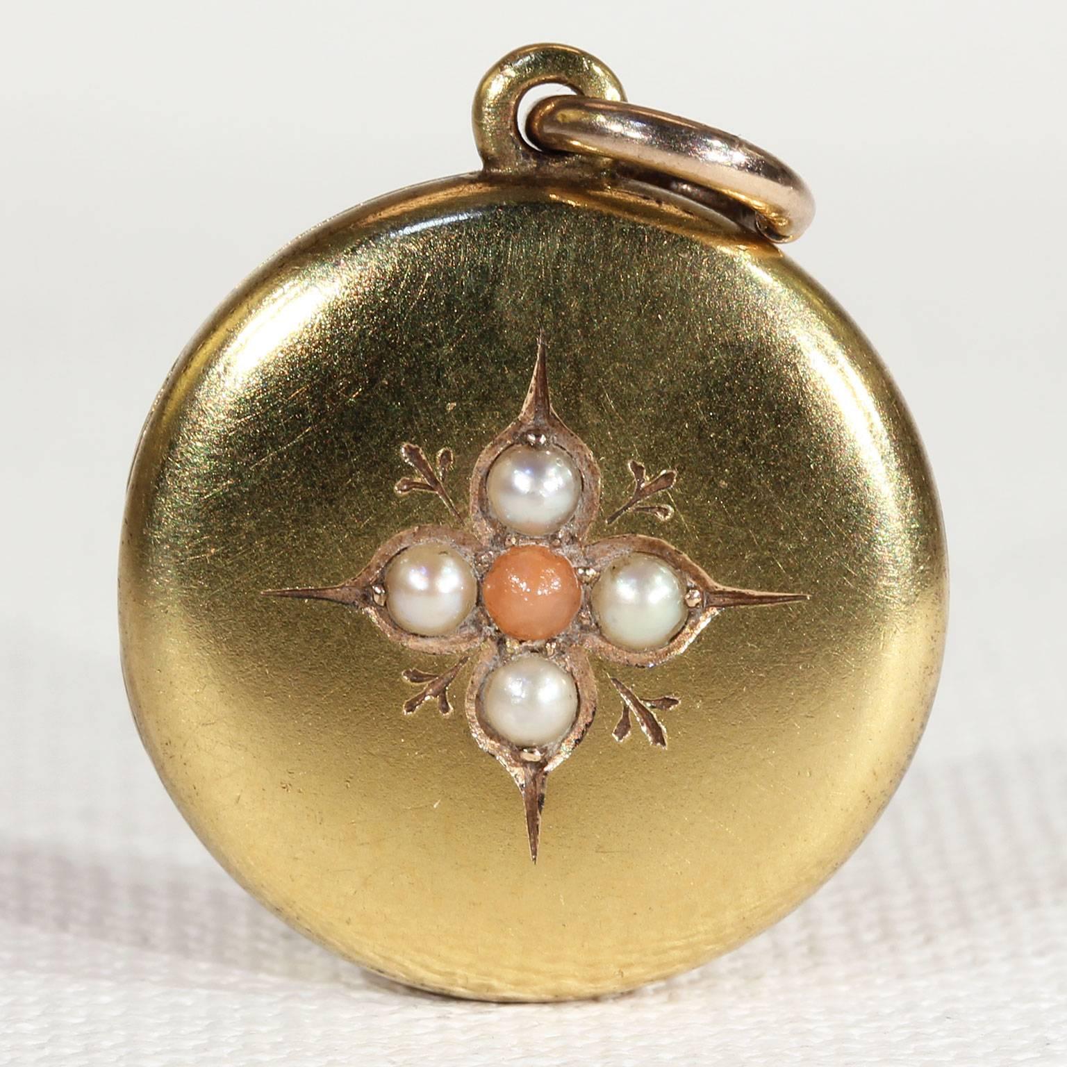 This fabulous locket showcases an elaborate and detailed anchor in rich blue enamel on one side and is set with four smooth and glowing pearls and a cabochon of coral on the other. It was hand crafted in 15 karat gold and is inscribed on the inside