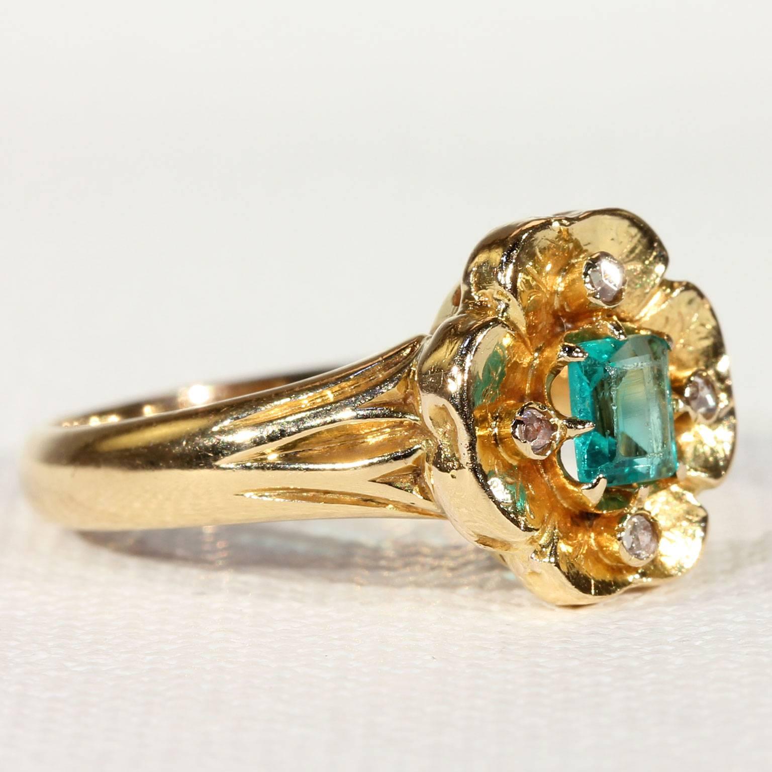 This gorgeous Victorian ring is set with a glowing hand cut emerald of lovely clarity with a stunning ‘middle of the Amazon’ green color. The gem forms the center of a pansy flower or maybe a four-leafed clover, each petal is delicately engraved and