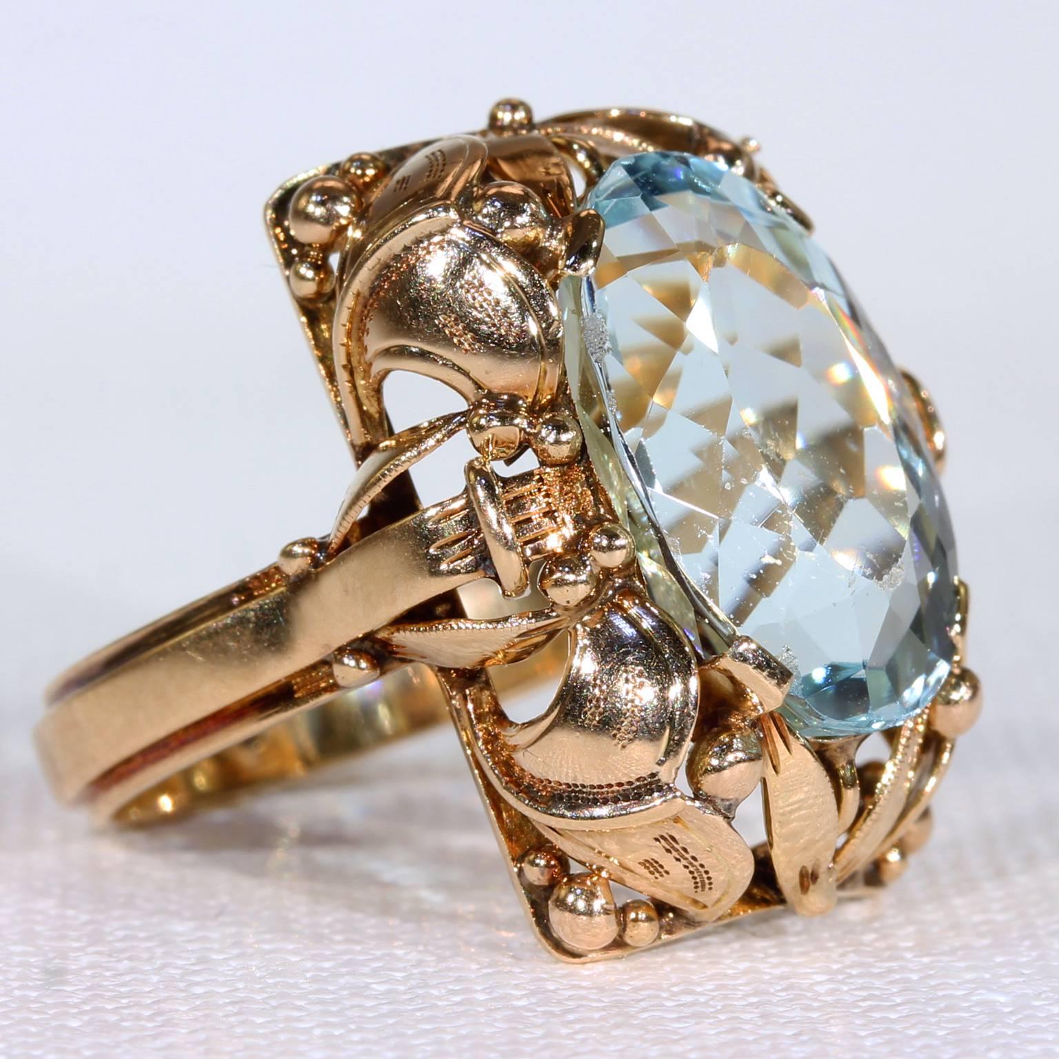 This Retro era aquamarine and gold ring was hand crafted with lovely detail around 1950. The baby blue oval aquamarine stone measures 16 x 11 x 7.8 mm and weighs approximately 7 carats. The stone is set in a 14 karat gold face which features a