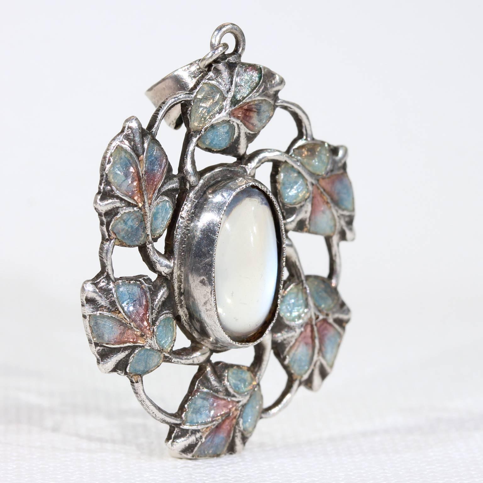 This antique, Arts and Crafts silver and moonstone pendant was handcrafted around 1910. It is attributed to Jessie M King who designed for Liberty of London. The silver pendant is set with a lively blue 2.6 carat cabochon moonstone and highlighted