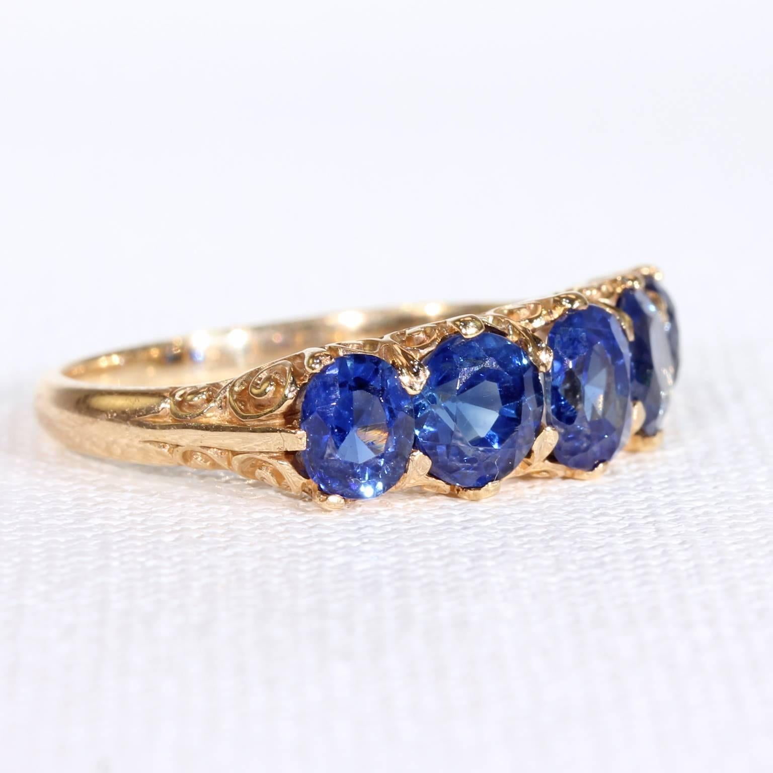 This antique Victorian natural sapphire and gold ring was handcrafted in England, around 1890. This ring holds five natural, untreated bright sapphires in a mesmerizing shade of rich cornflower blue. Together, this ring boasts 3.4  total carats of
