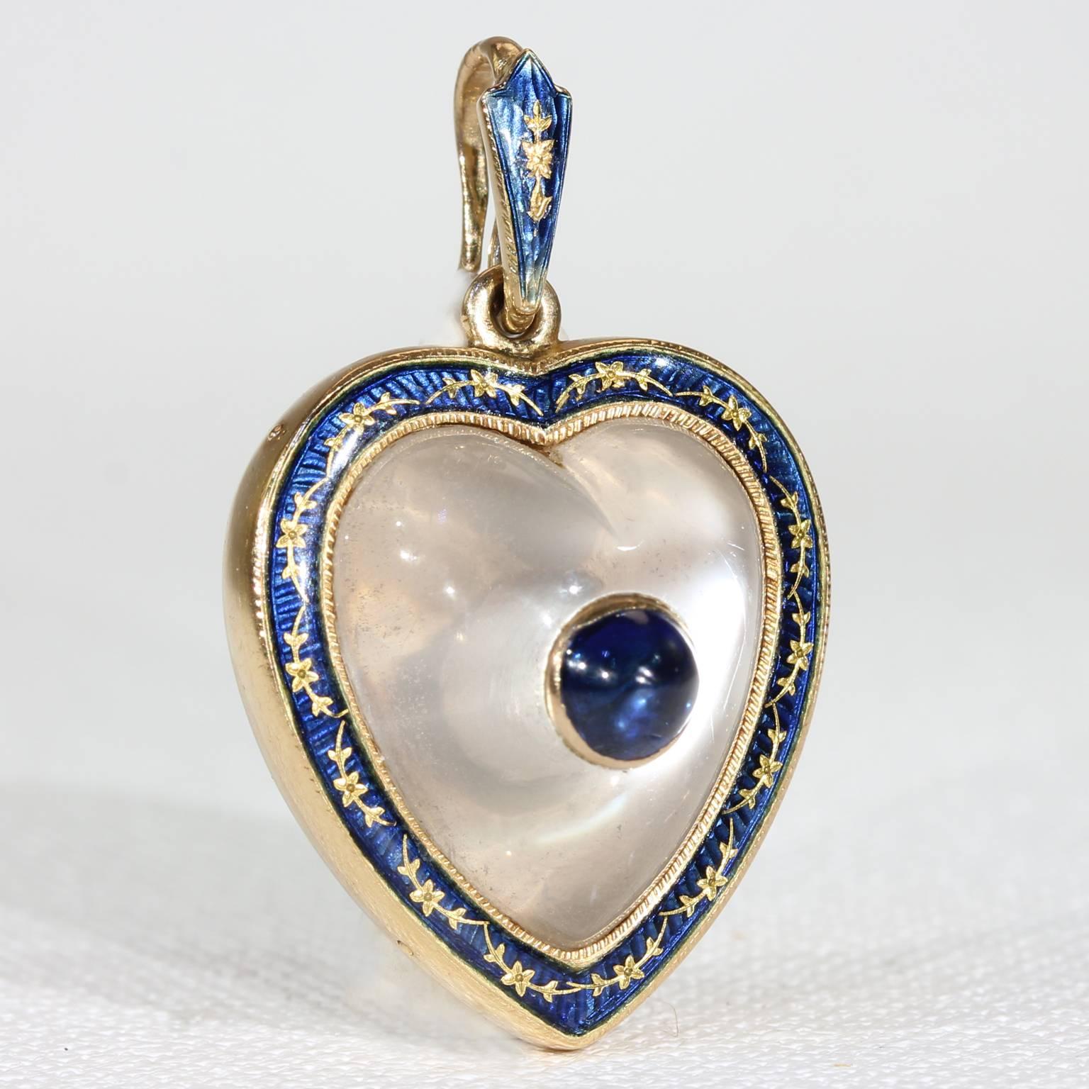 This elegant antique Victorian moonstone heart pendant was handcrafted around 1890, most likely in America. It was made in 14 karat gold and features a pretty blue cabochon cut sapphire which has been bezel set into the center of moonstone. The