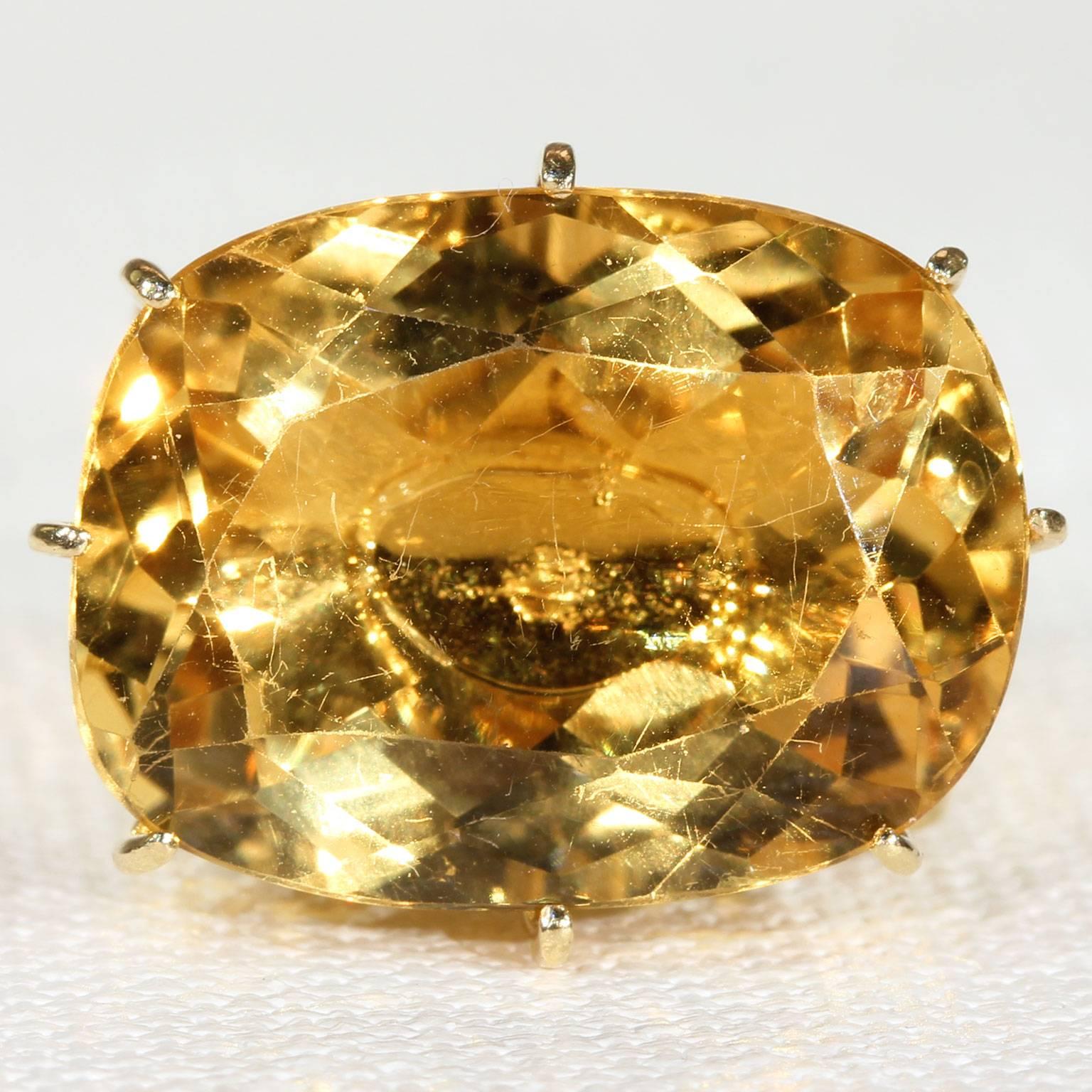 This bold retro cocktail ring was handcrafted around 1960. It’s a vintage piece featuring a 14.34 carat, oval cut, faceted citrine stone, set in 18 karat gold. The citrine measures 15 x 20 x 8.2 mm. On the side shoulder of this unique piece is a