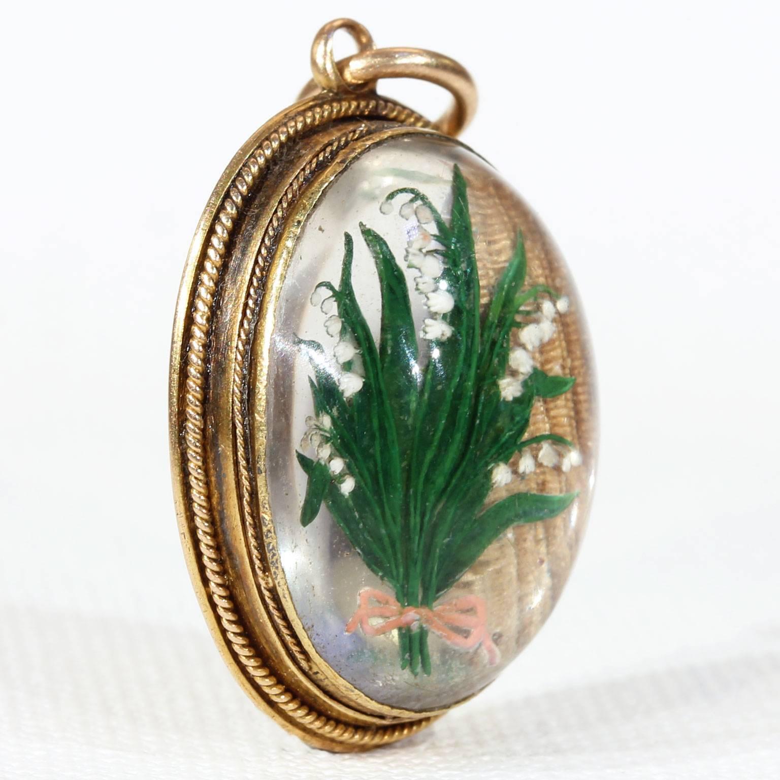 This reverse crystal intaglio is made from a smooth cabochon of rock crystal with a lily of the valley flower carved expertly into the flat back and then oil painted with bright colors to bring it to richly detailed life. The crystal is set into a
