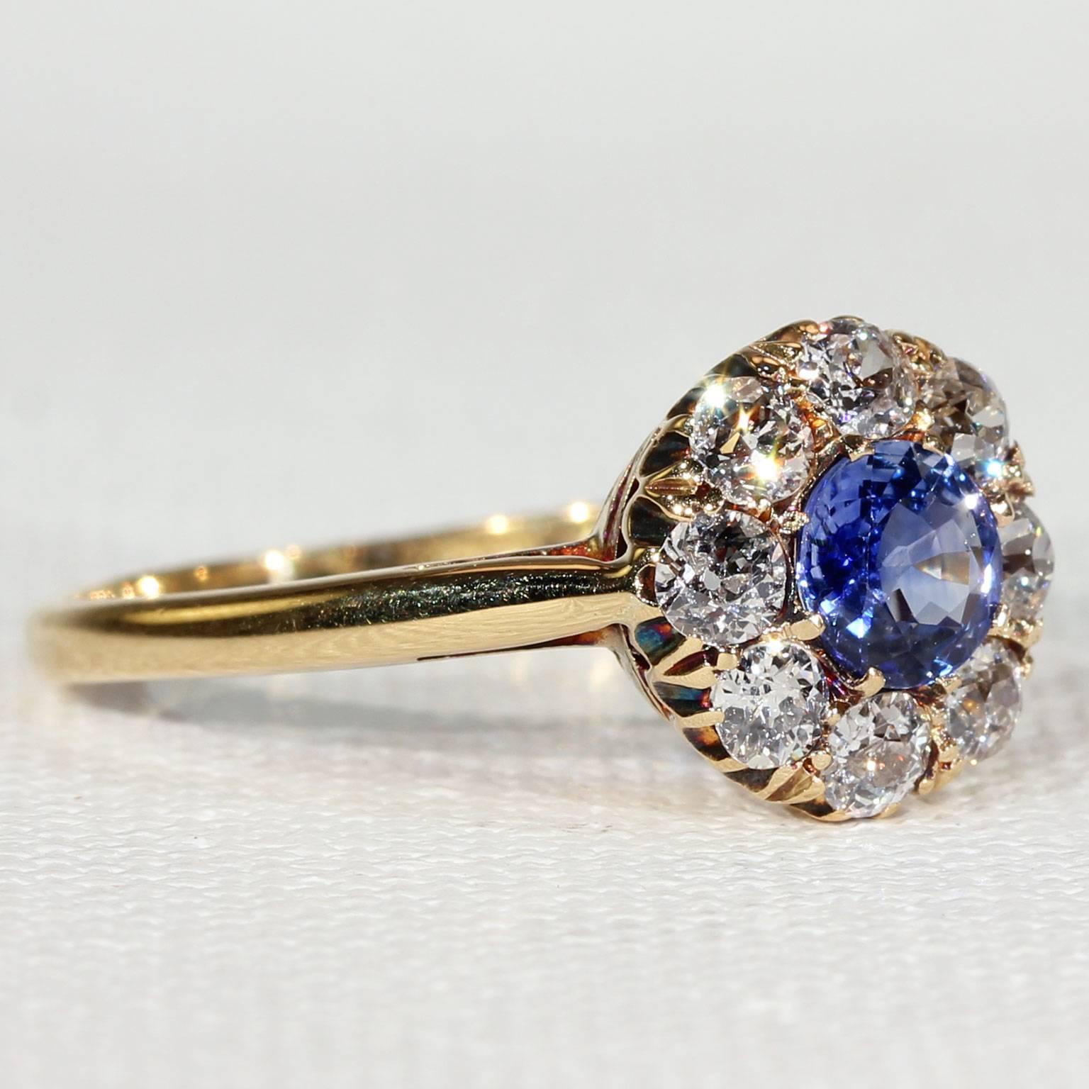 This antique sapphire and diamond cluster ring was hand crafted in England during the Victorian Era, around 1900. The center round faceted sapphire weighs approximately .65 carats. The lovely blue center is surrounded by eight Old European cut