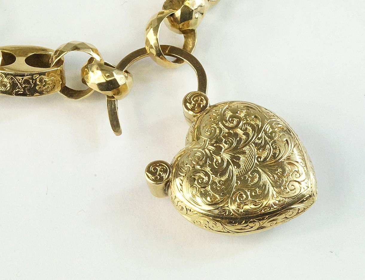 A bracelet of beautifully engraved larger links with faceted smaller links connects with a clear case back/engraved front heart padlock in 15k yellow gold. The heart is 22 mm wide. The bracelet is 7 inches in length and can certainly be worn