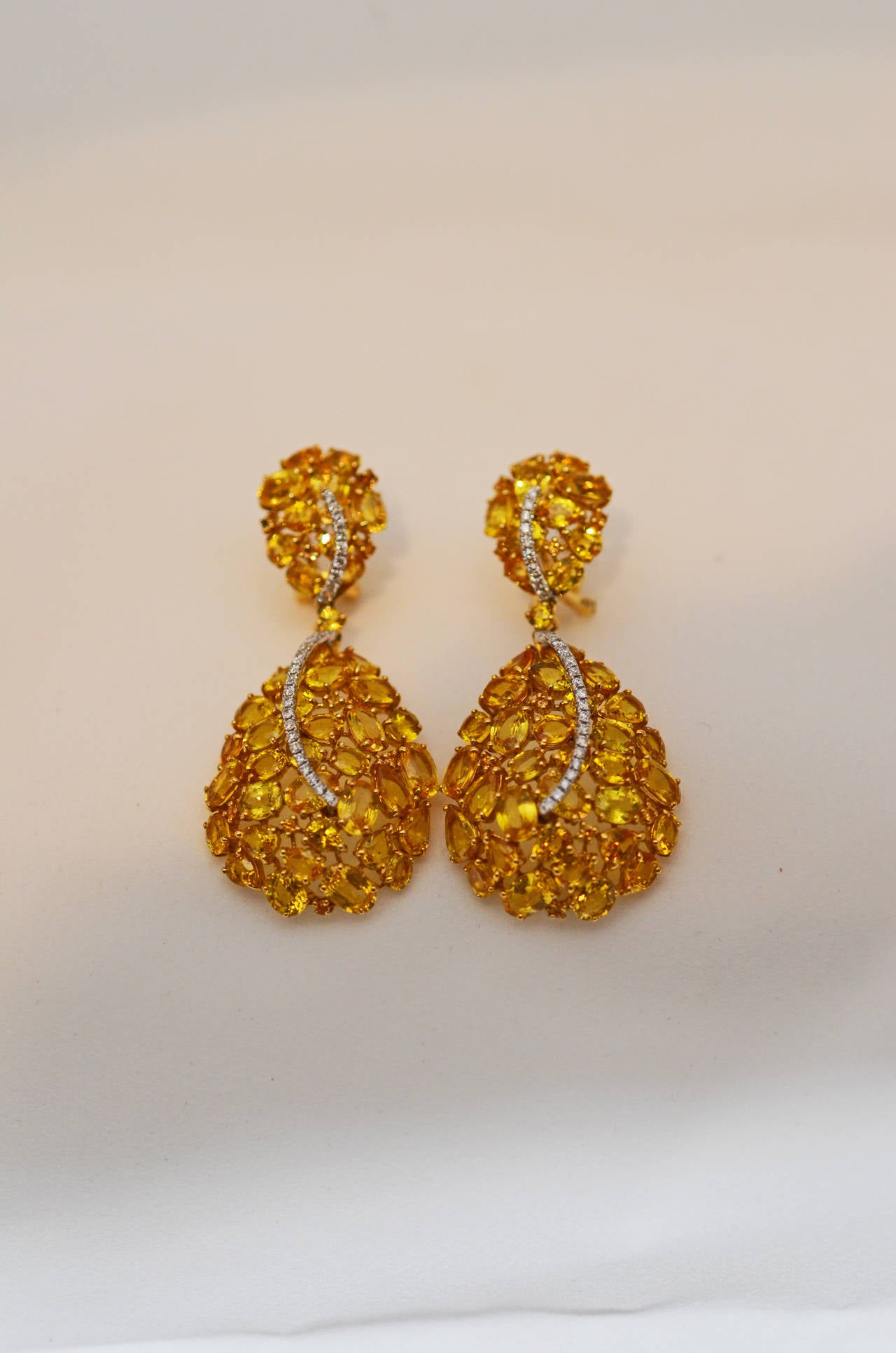 One pair of yellow sapphire and diamond earrings.  There are 32.00cts of medium to strong colored natural yellow sapphire.  There are .57cts of round brilliant cut diamonds.  The earrings are set in 18k yellow gold.