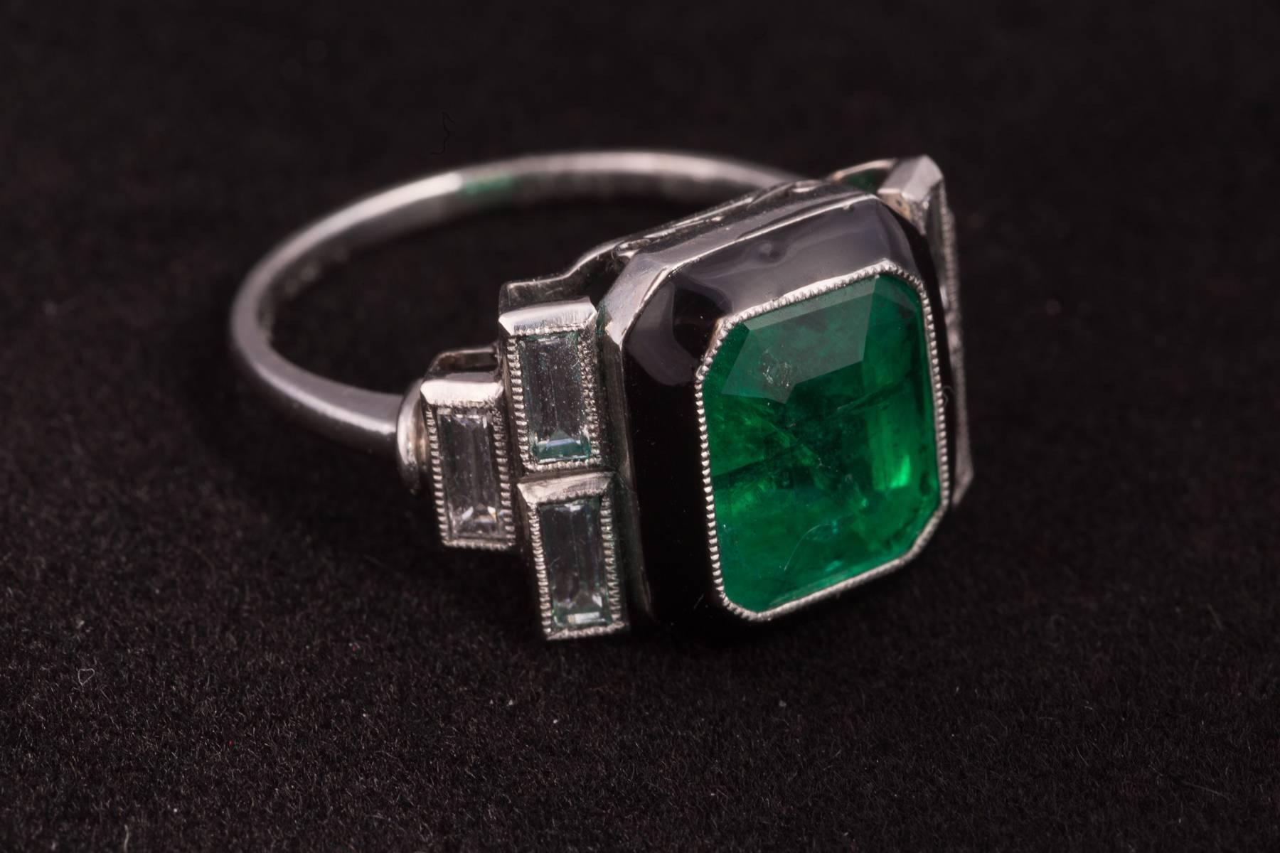 Columbian Emerald and baguette diamond ring. The Emerald measures 9.40x8.60x6.35mm and weighs approx. 3.55cts. There are 6 baguette cut diamonds weighing approx. .90cts total. The mounting in platinum with black enamel circa 1945. Ring size 7.5