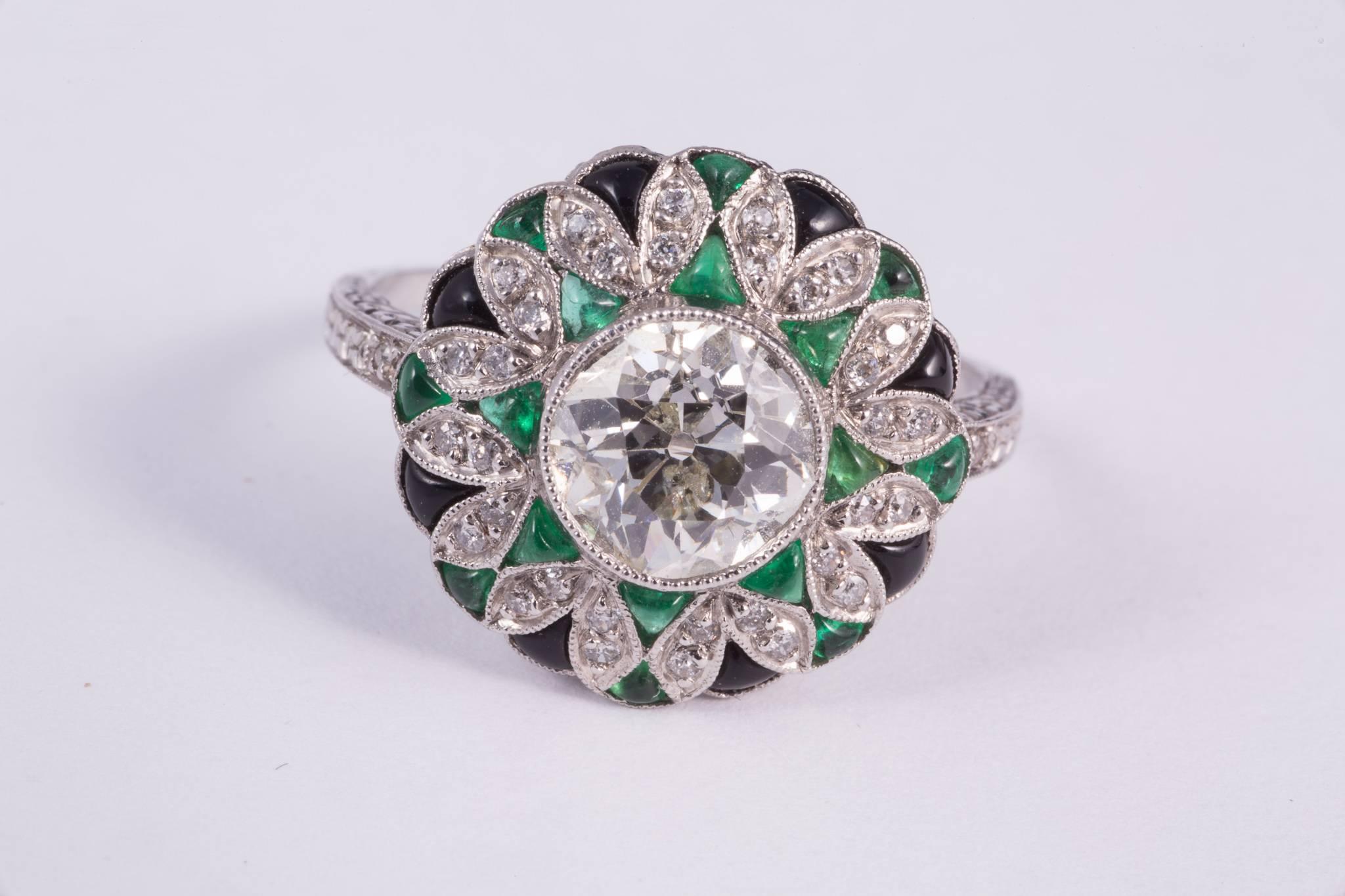 Magnificent Art Deco style diamond, emerald and onyx ring. The center european cut diamond weighs approx. 1.57cts, has H-I color and SI1-SI2 clarity. It is bezel set and is surrounded with 36 genuine round cut diamonds weighing approx .18cts total.