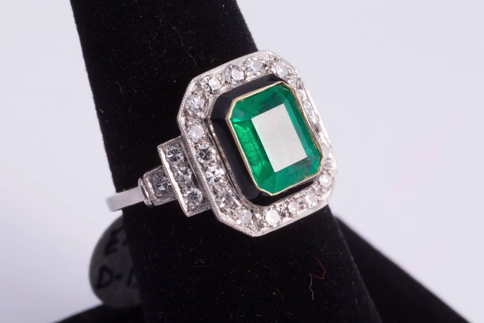 Gorgeous, natural, approx. 2.50ct emerald cut emerald in the center of the ring. The center stone is bezel set in gold and had a black enamel border. Stepping down from the enamel there are a total of 26 diamonds around and diamonds on the sides of
