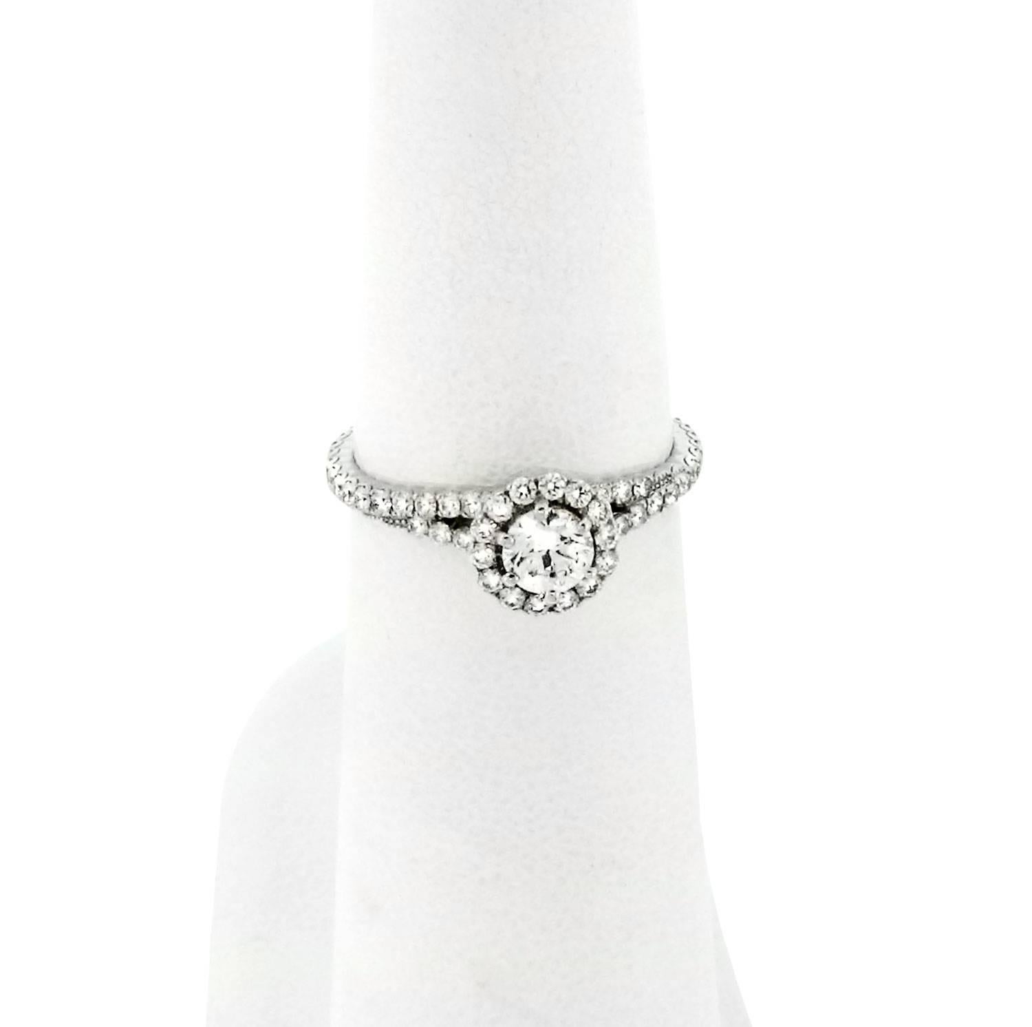 This platinum engagement ring is a masterful design with the highest quality of materials used in it's creation. White diamonds glitter from every angle and bring the focus to the round-cut center diamond. This ring boasts a unique design with what